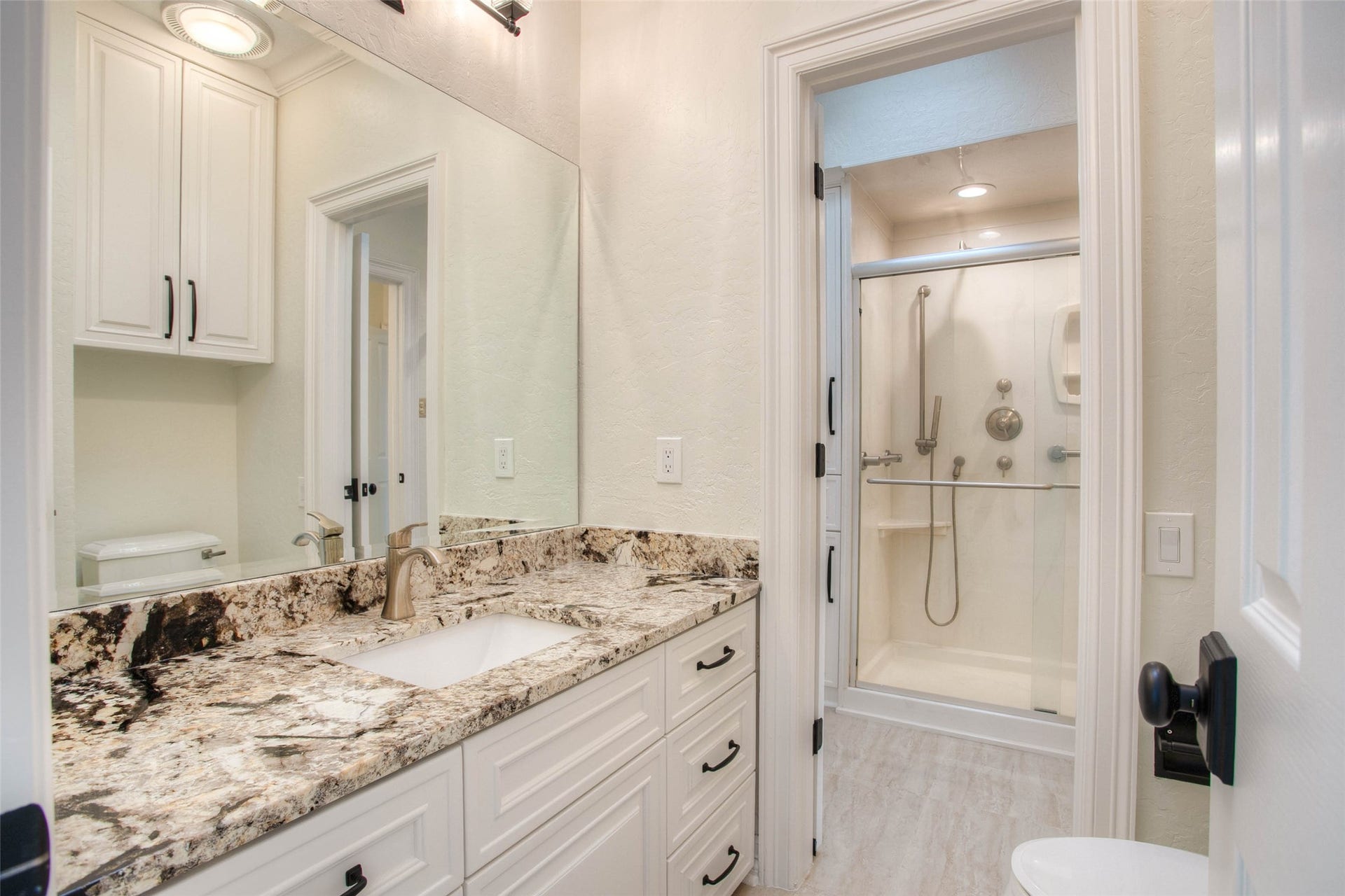 12092 Sagittarius Drive E, Willis, TX 77318 Luxuriate in a Hollywood-style guest bath featuring elegant granite countertops, ample storage, and a sleek, modern shower.