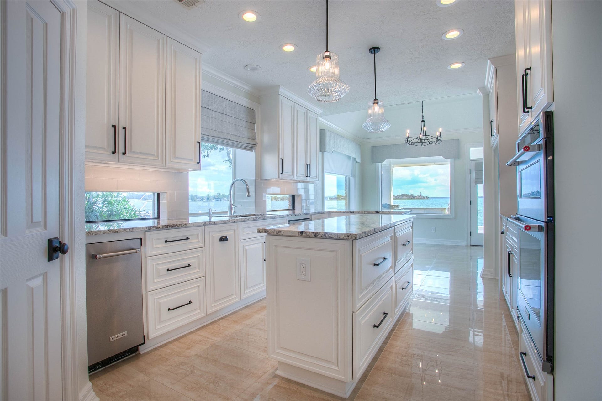 12092 Sagittarius Drive E, Willis, TX 77318 Elegant kitchen with pristine white cabinetry, gleaming granite countertops, and stainless steel appliances. Separate ice maker. Large windows offer stunning water views, filling the space with natural light.