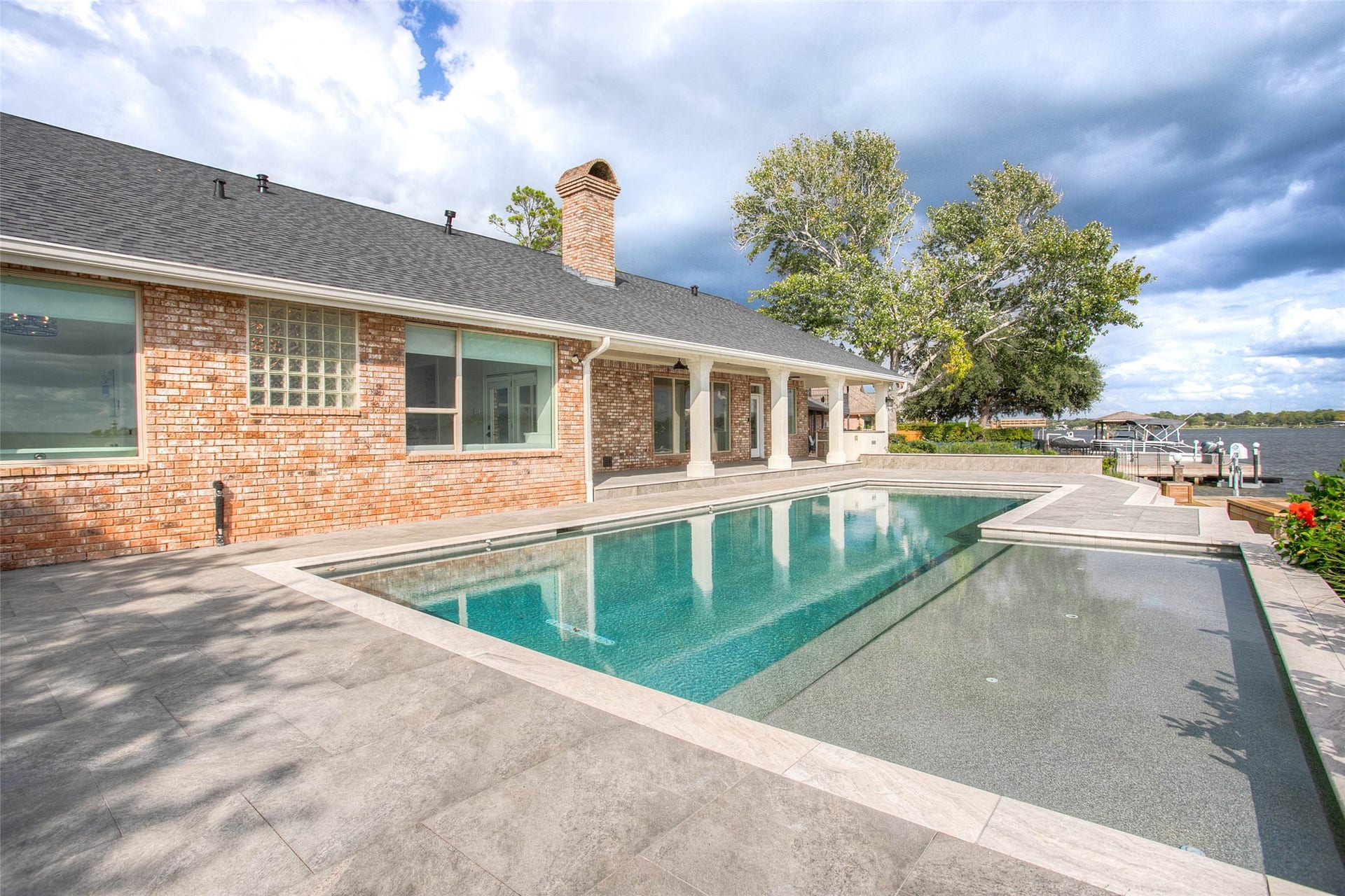 12092 Sagittarius Drive E, Willis, TX 77318 Stunning waterfront property featuring a luxurious pool and spacious patio, perfect for relaxing and entertaining with picturesque lake views.