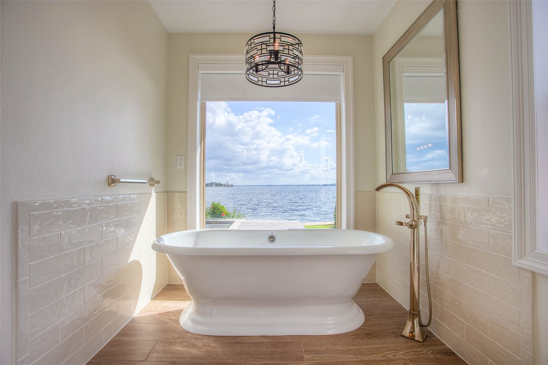 12092 Sagittarius Drive E, Willis, TX 77318 Luxurious bathroom featuring a freestanding tub with breathtaking lake views, complemented by elegant tile and modern fixtures.