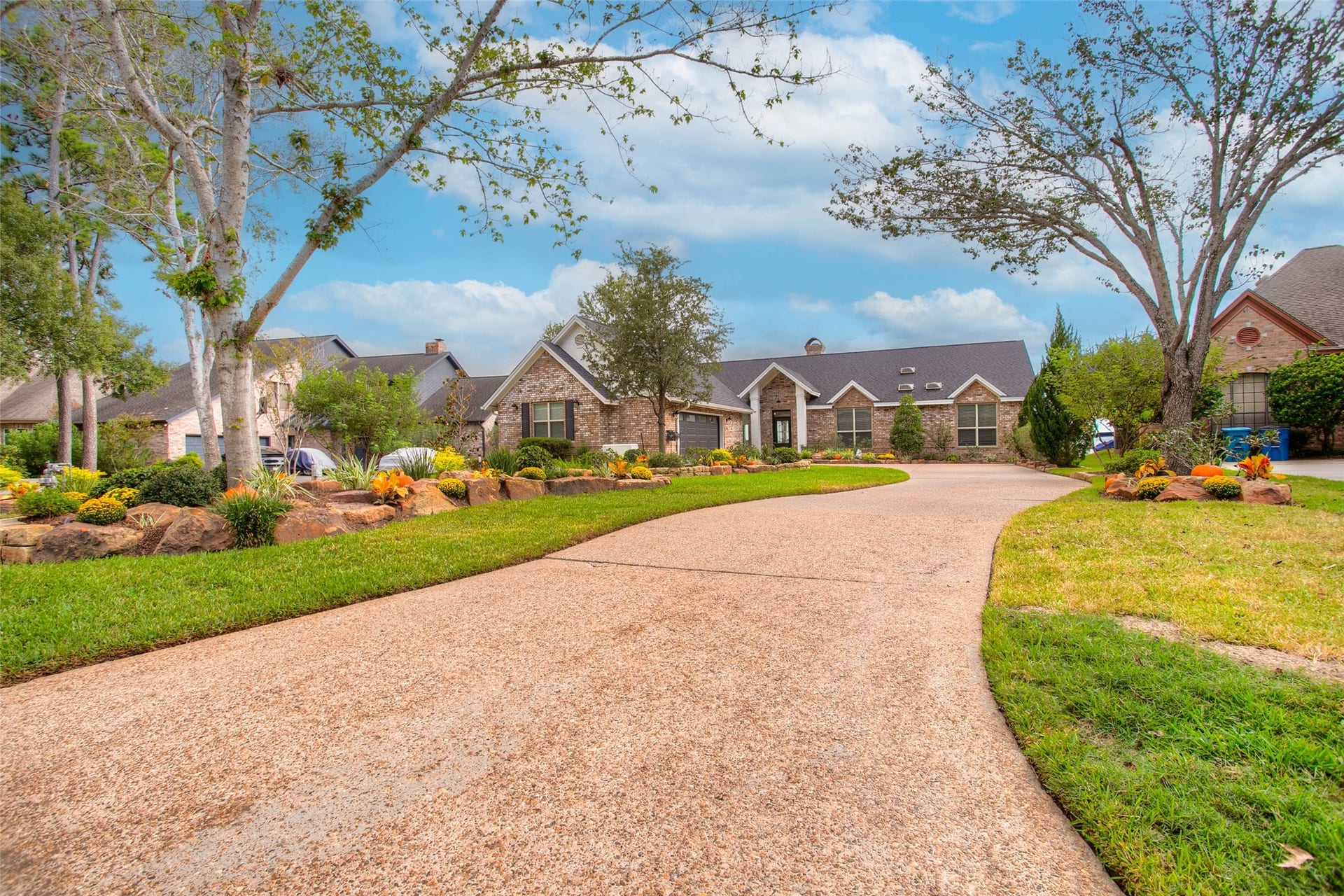 12092 Sagittarius Drive E, Willis, TX 77318 Stunning single-story home with charming brick exterior, framed by lush landscaping and a long, welcoming driveway.