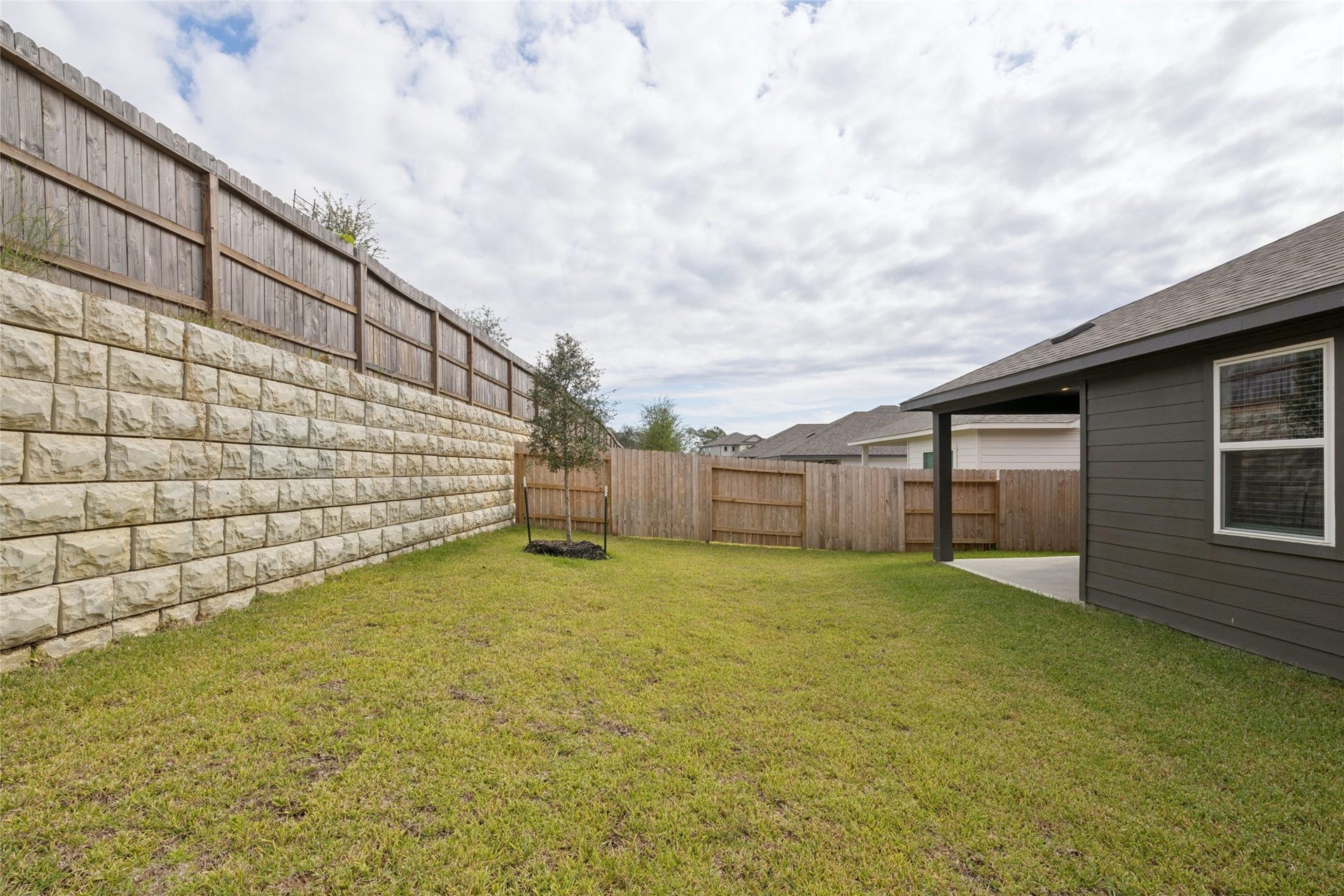 384 Sunrise Ranch Dr, Montgomery, TX 77316 Spacious backyard with lush grass, privacy fencing, and a retaining wall, perfect for outdoor activities and relaxation.