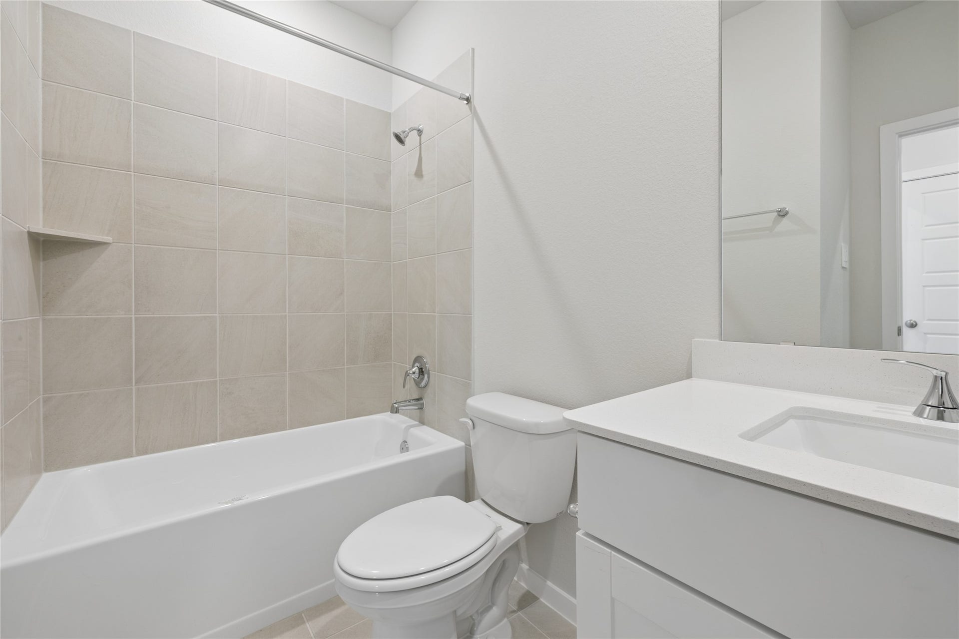 384 Sunrise Ranch Dr, Montgomery, TX 77316 Modern bathroom featuring a sleek vanity with ample storage, a spacious bathtub with neutral tile surround, and bright lighting.