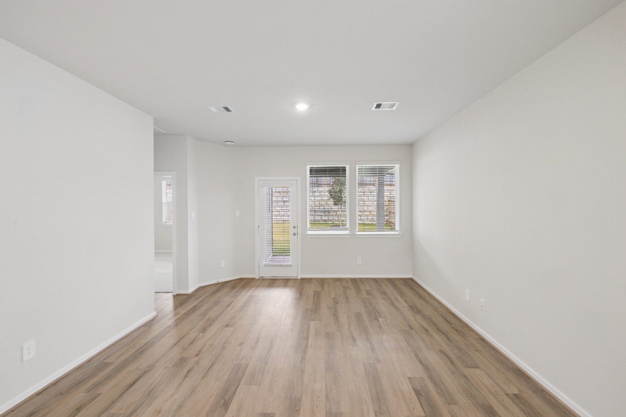384 Sunrise Ranch Dr, Montgomery, TX 77316 Bright and airy living space with sleek hardwood floors, large windows, and a door leading to the backyard, perfect for relaxing or entertaining.