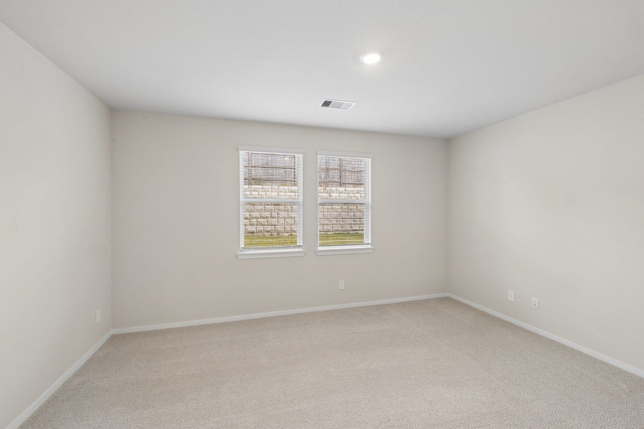 384 Sunrise Ranch Dr, Montgomery, TX 77316 Bright, spacious room with neutral walls and carpeting, featuring two windows that invite natural light.