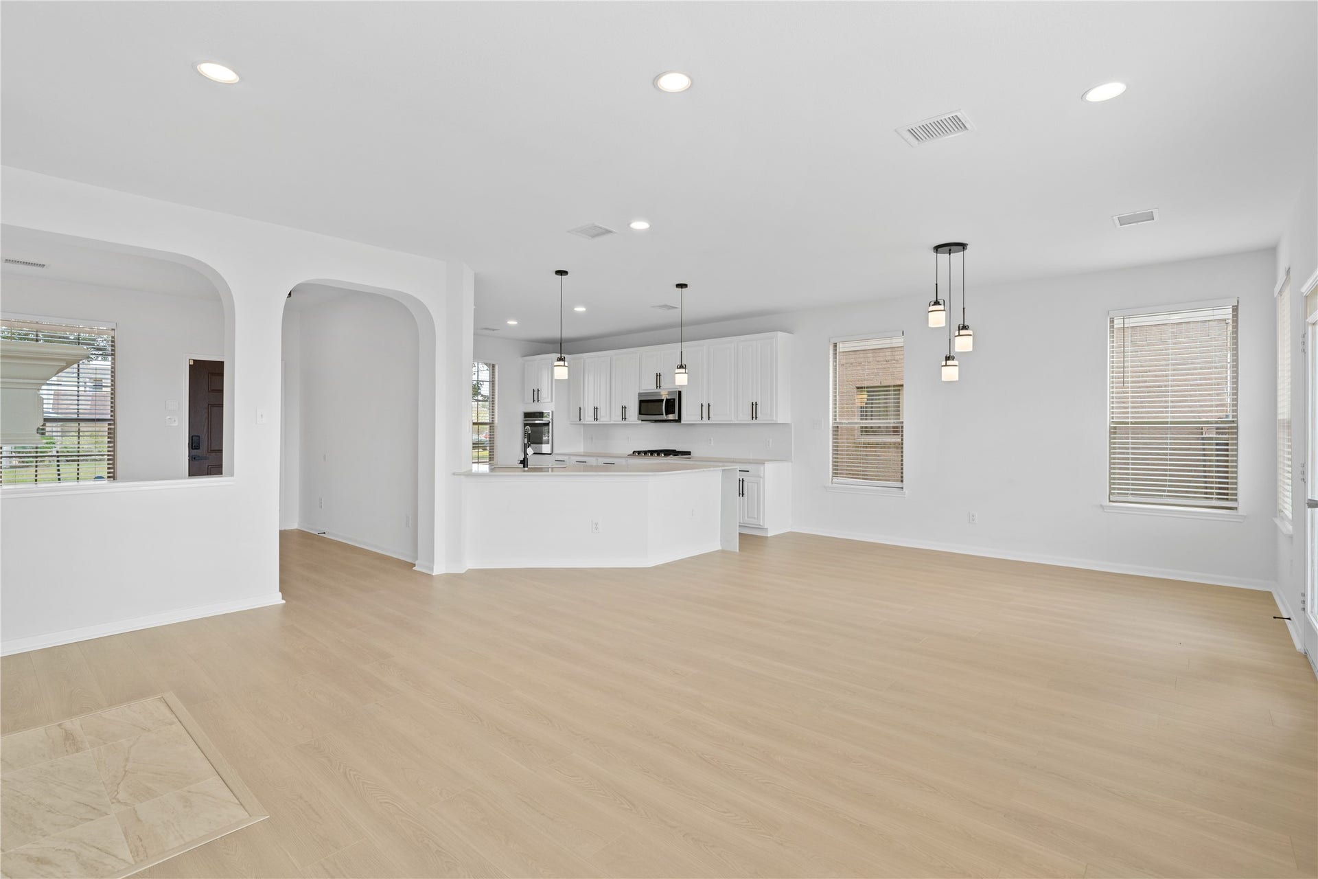 21611 Manitou Falls Lane, Katy, TX 77449 Living Area & Kitchen Wide-angle view showcases the spacious main living area flowing directly into the kitchen, accented by arched architectural openings, modern lighting, and plentiful natural light.