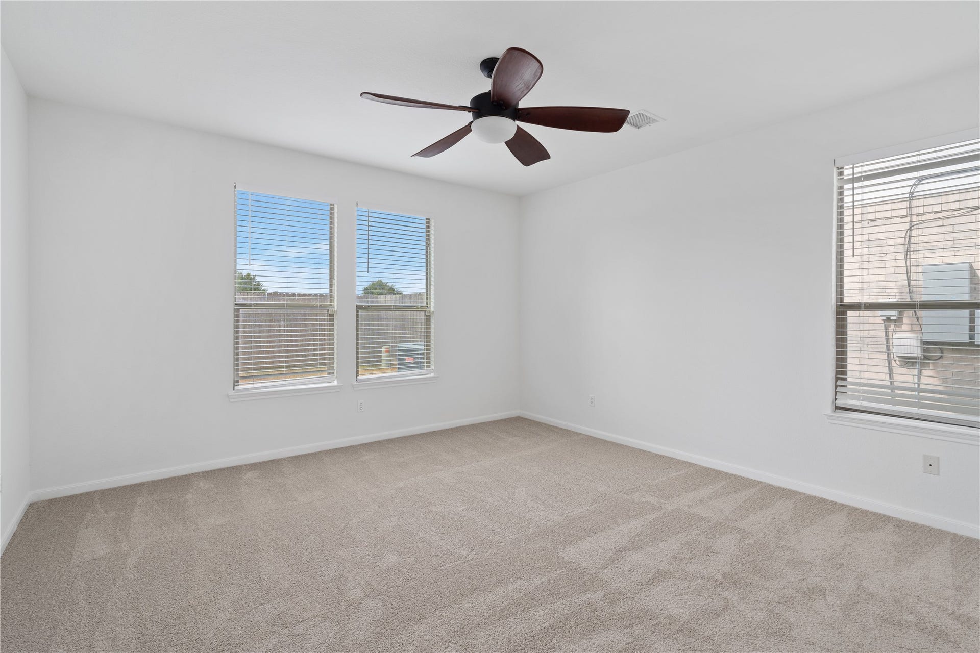 21611 Manitou Falls Lane, Katy, TX 77449 Bedroom Spacious bedroom with neutral carpeting, a ceiling fan, and three windows that bring natural light into the room.