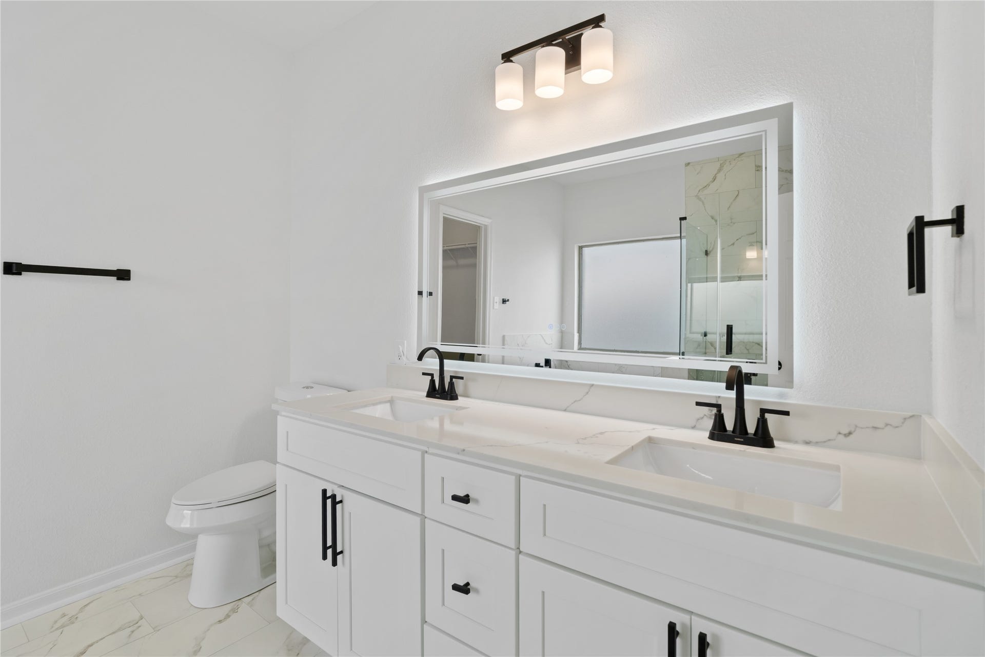 21611 Manitou Falls Lane, Katy, TX 77449 Primary Bathroom Double-sink vanity offers abundant counter and cabinet space, complemented by matte-black fixtures and a large illuminated mirror.