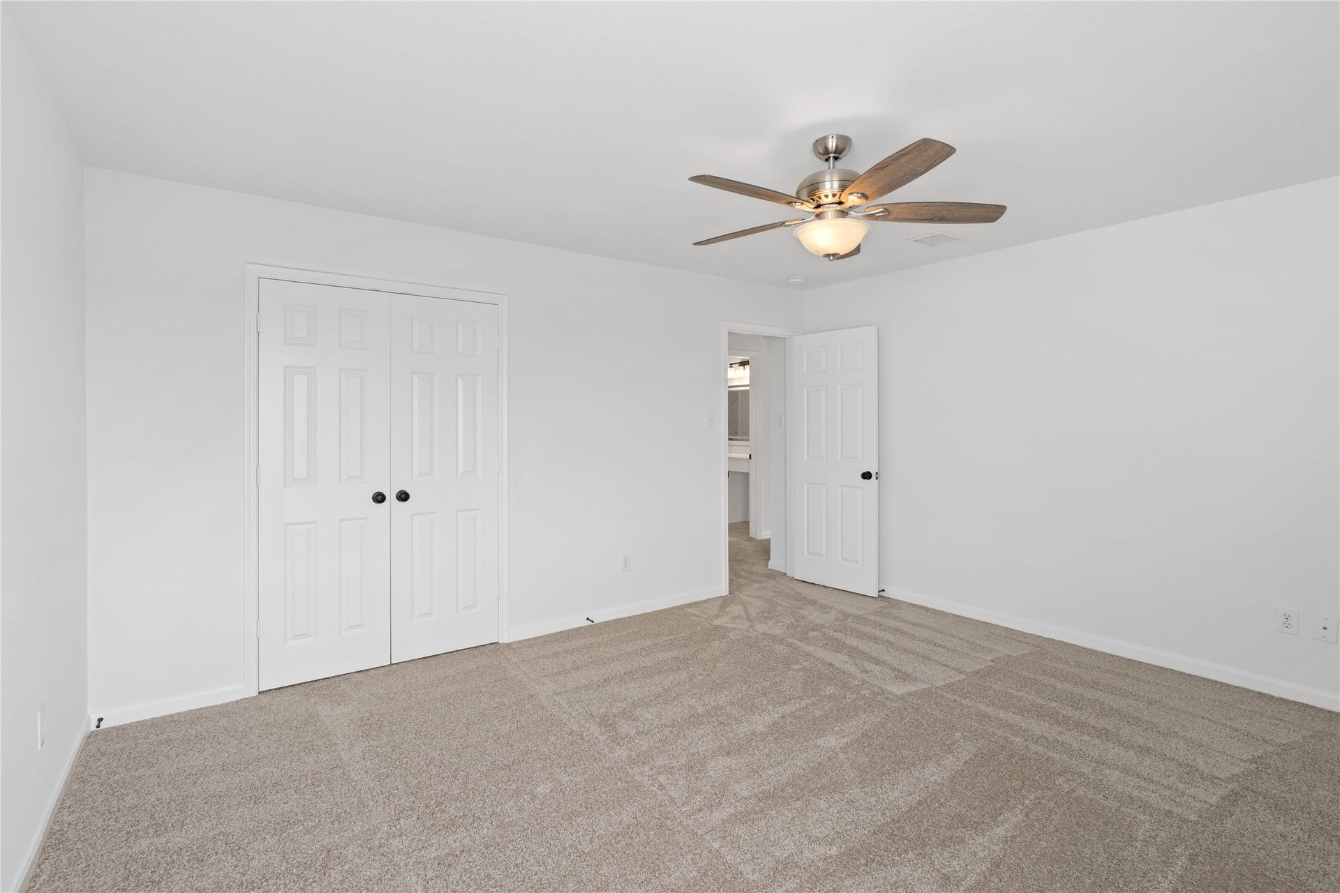 21611 Manitou Falls Lane, Katy, TX 77449 Bedroom Alternate view highlights the generous proportions, double-door closet, neutral carpeting, and ceiling fan with integrated lighting.