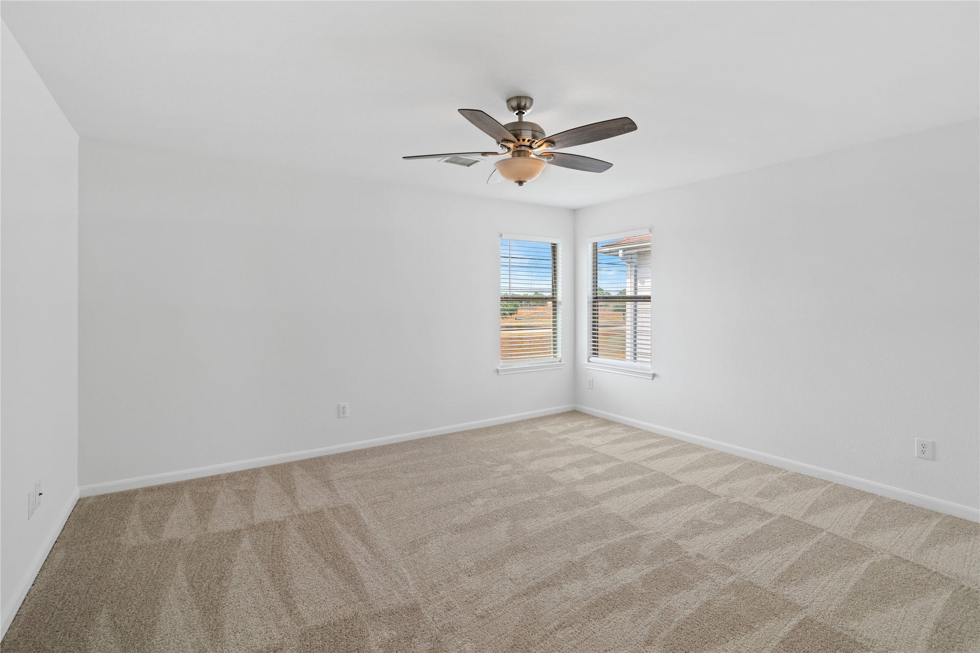 21611 Manitou Falls Lane, Katy, TX 77449 Bedroom Spacious carpeted bedroom with crisp neutral finishes, a ceiling fan, and two windows providing abundant natural light.