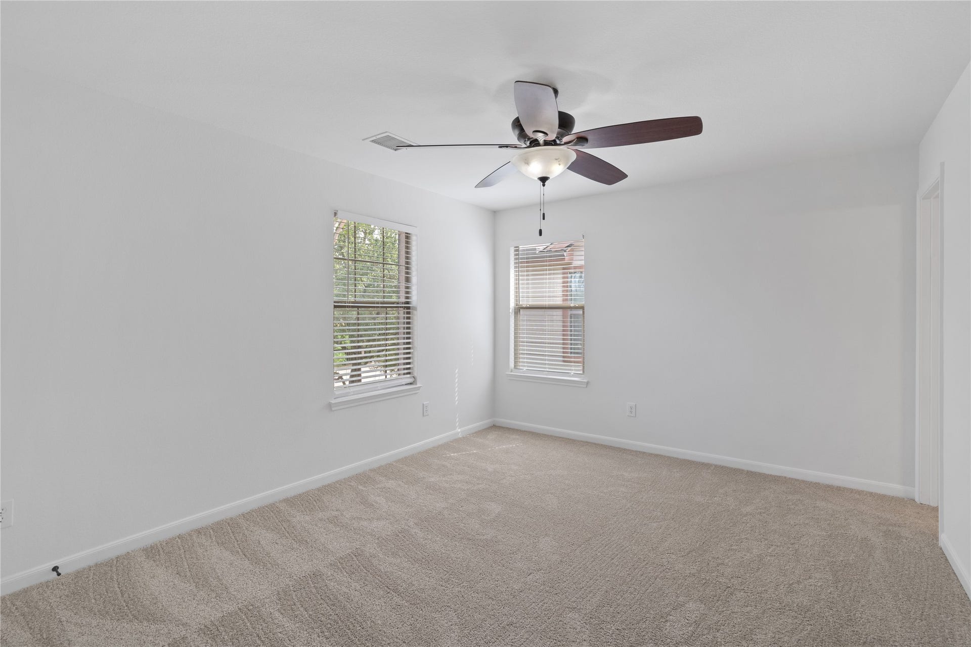 21611 Manitou Falls Lane, Katy, TX 77449 Bedroom Generously sized carpeted bedroom with two windows, a ceiling fan, and a bright neutral color palette.