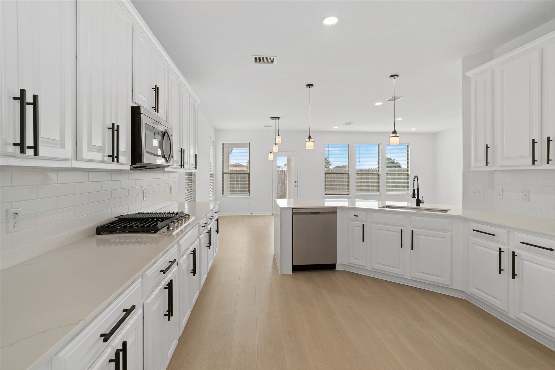 21611 Manitou Falls Lane, Katy, TX 77449 Kitchen Spacious kitchen features extensive cabinetry and counter space, stainless steel dishwasher, peninsula with sink, modern black fixtures, and an open sightline into the adjoining living and dining areas.