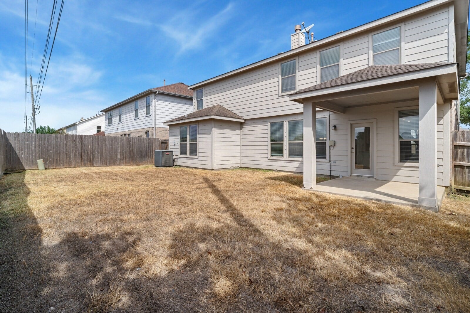 21611 Manitou Falls Lane, Katy, TX 77449 Backyard Fenced backyard provides an open lawn area and a covered patio directly accessible from the home, offering flexible space for outdoor seating and recreation.