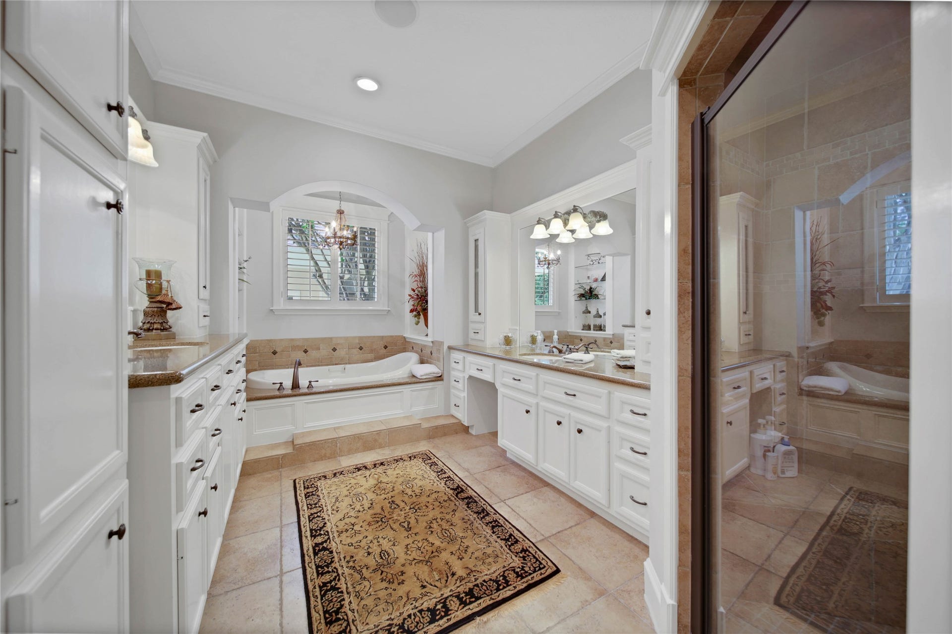 12635 Hunters Canyon Lane, Cypress, TX 77429 The primary bathroom features elegant cabinetry, a large walk-in shower, and dual vanities with an abundance of built-in cabinets, all enhanced by warm tile flooring and soft lighting. There are two walk-in custom closets with shelving, built-in chest of drawers, and shoe storage.