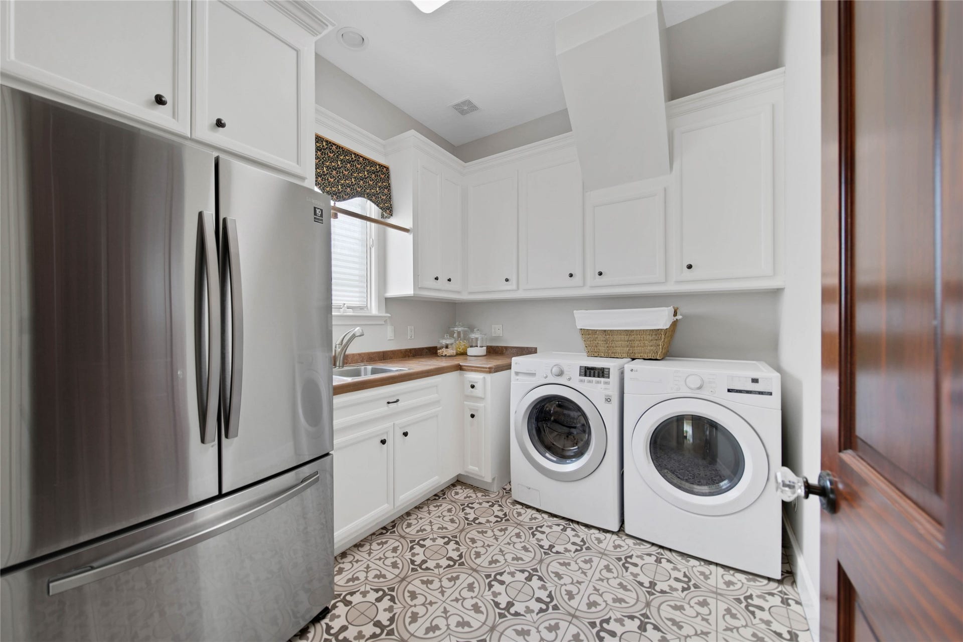 12635 Hunters Canyon Lane, Cypress, TX 77429 The laundry room with patterned tile flooring, has ample white cabinetry for storage, room for a full size refrigerator and a wet sink. There is also a laundry chute and built-in ironing board for convenience.