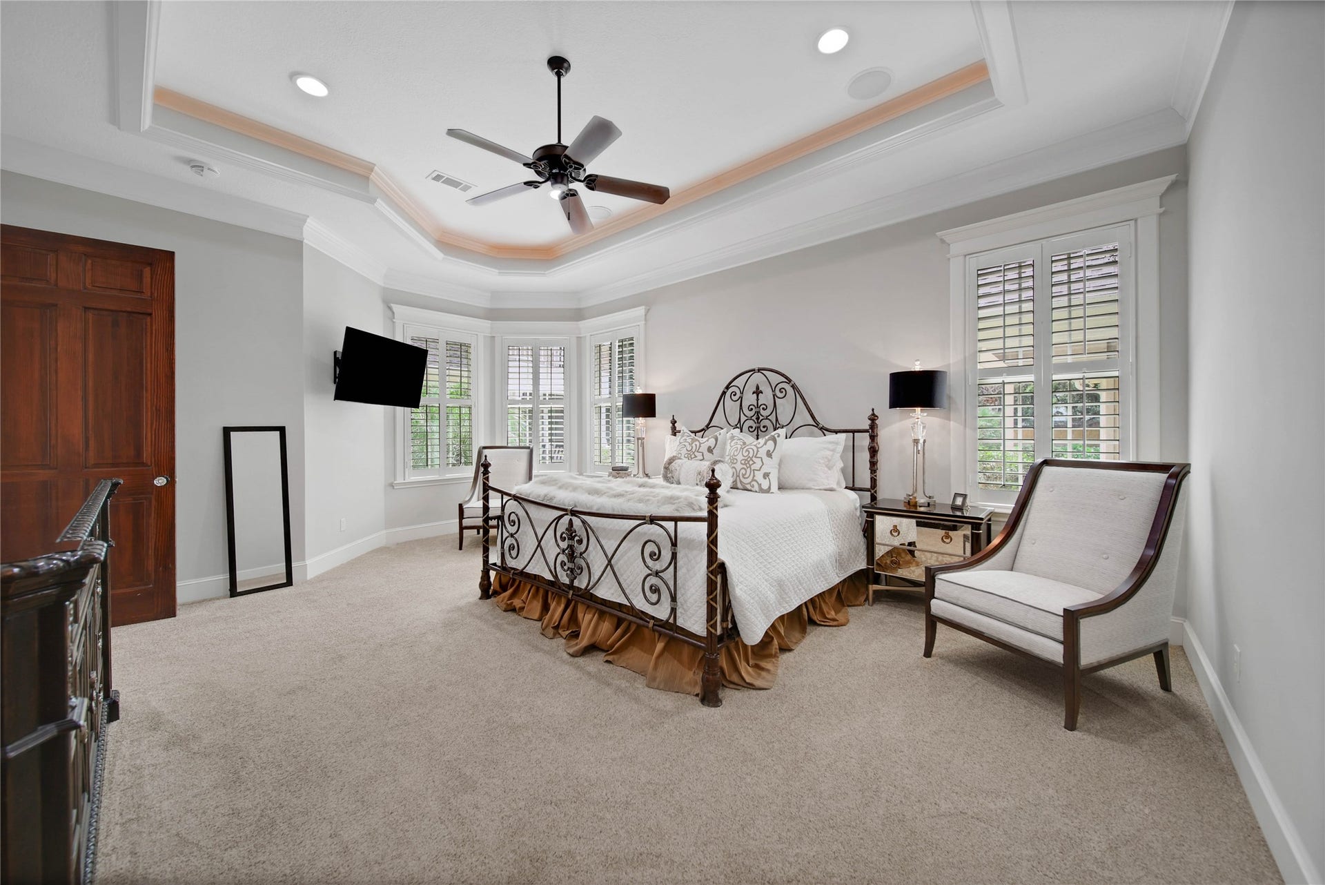 12635 Hunters Canyon Lane, Cypress, TX 77429 Located on the opposite side of the home is the oversized primary bedroom featuring a tray ceiling with cove lighting and cozy carpeting. Natural light streams through large windows with plantation shutters, complementing the soft neutral tones.