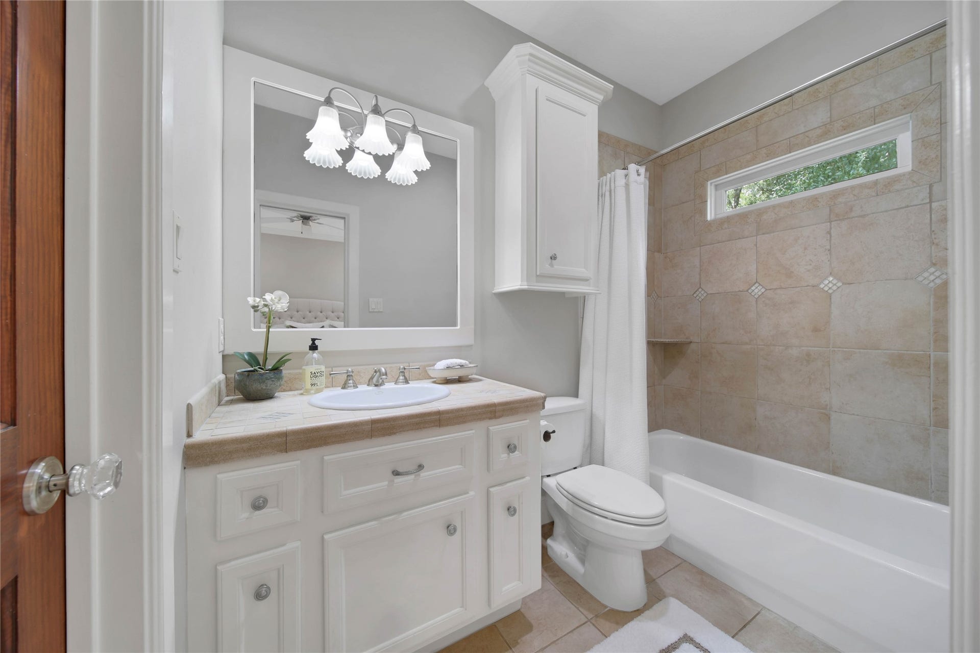 12635 Hunters Canyon Lane, Cypress, TX 77429 The ensuite bathroom features a sleek vanity with ample storage, a large mirror with stylish lighting, and a cozy tub/shower combo surrounded by warm-toned tiles.