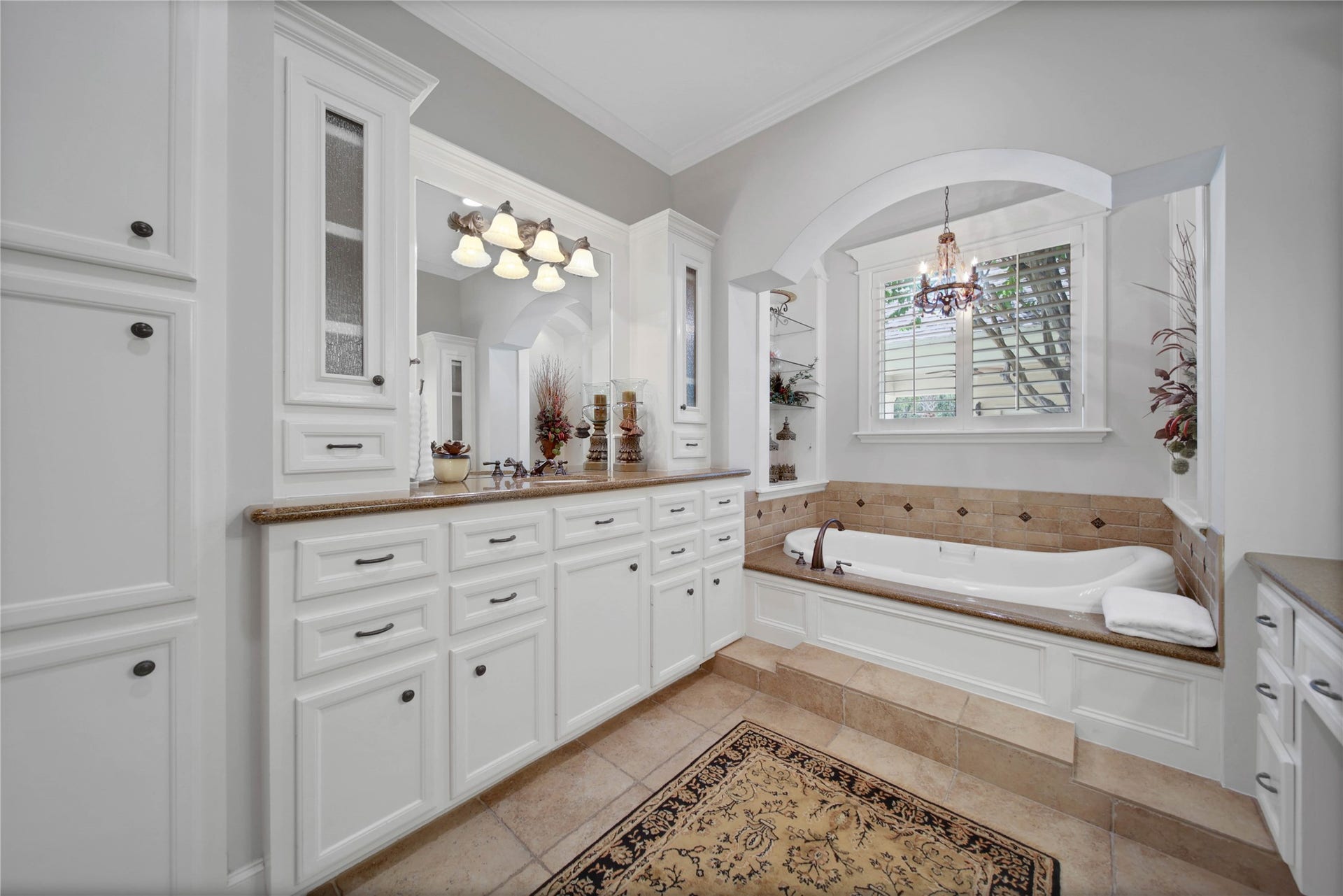 12635 Hunters Canyon Lane, Cypress, TX 77429 The primary bathroom features a luxurious raised built-in soaking tub under an arched opening surrounded by custom cabinetry and a spacious vanity with ample storage.