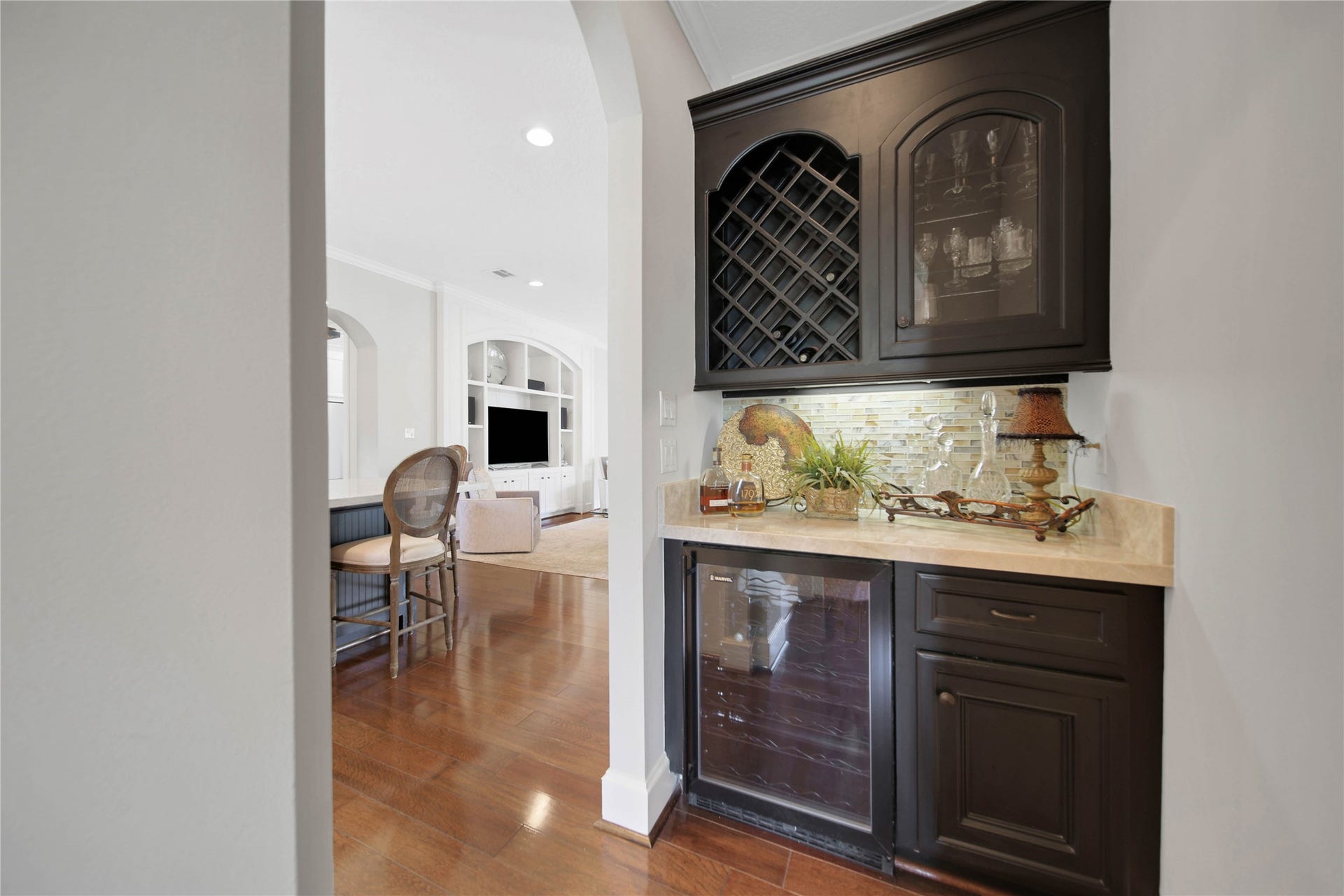 12635 Hunters Canyon Lane, Cypress, TX 77429 The elegant Butler's pantry/bar, with custom cabinetry and quartzite countertops, seamlessly connects to the spacious kitchen and living area with rich wood floors. There is a wine rack and wine refrigerator for added convenience when entertaining.