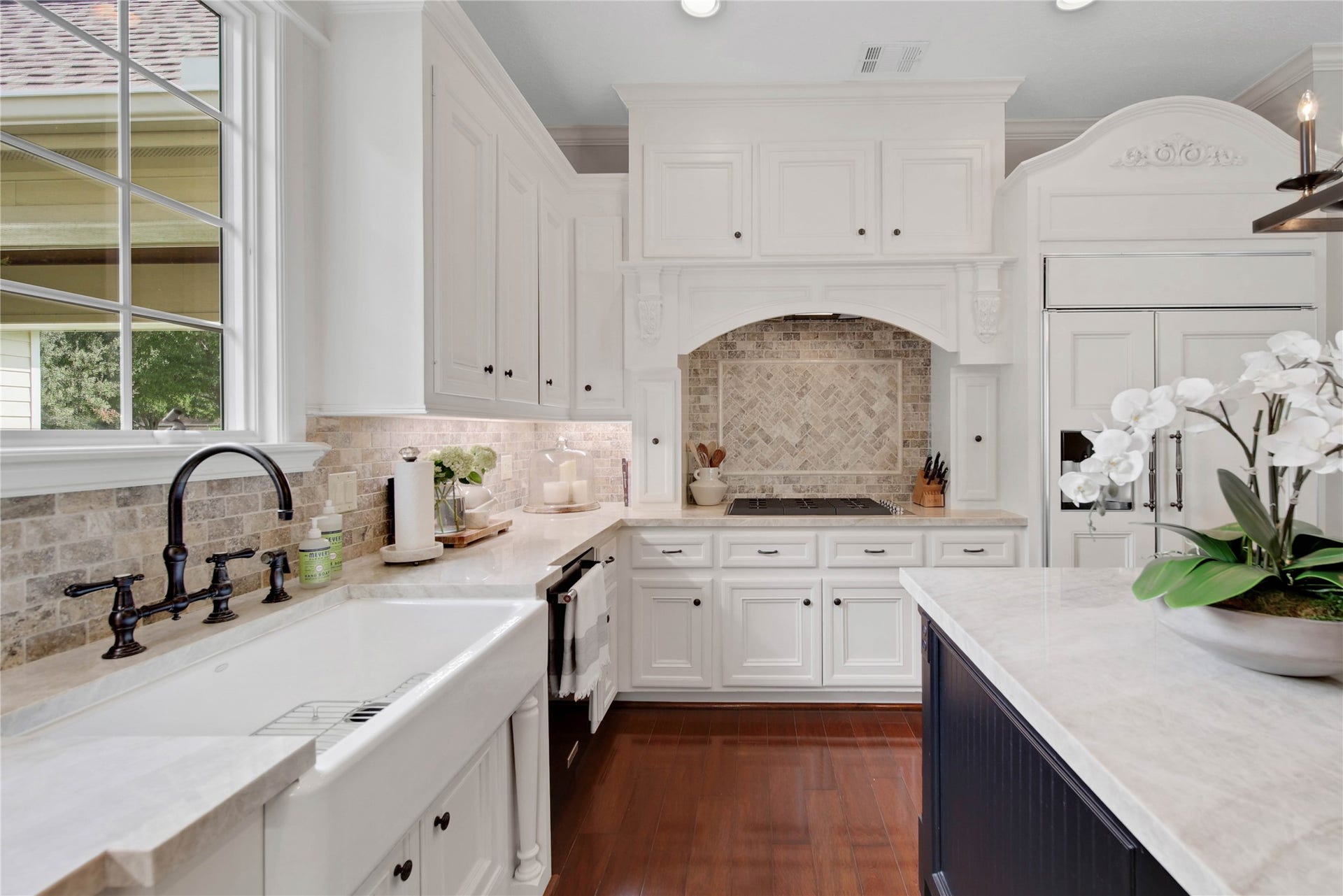 12635 Hunters Canyon Lane, Cypress, TX 77429 The kitchen features custom white cabinetry, a porcelain farmhouse sink, and a window over the sink. The cabinet front built-in refrigerator blends seamlessly for a sophisticated look.
