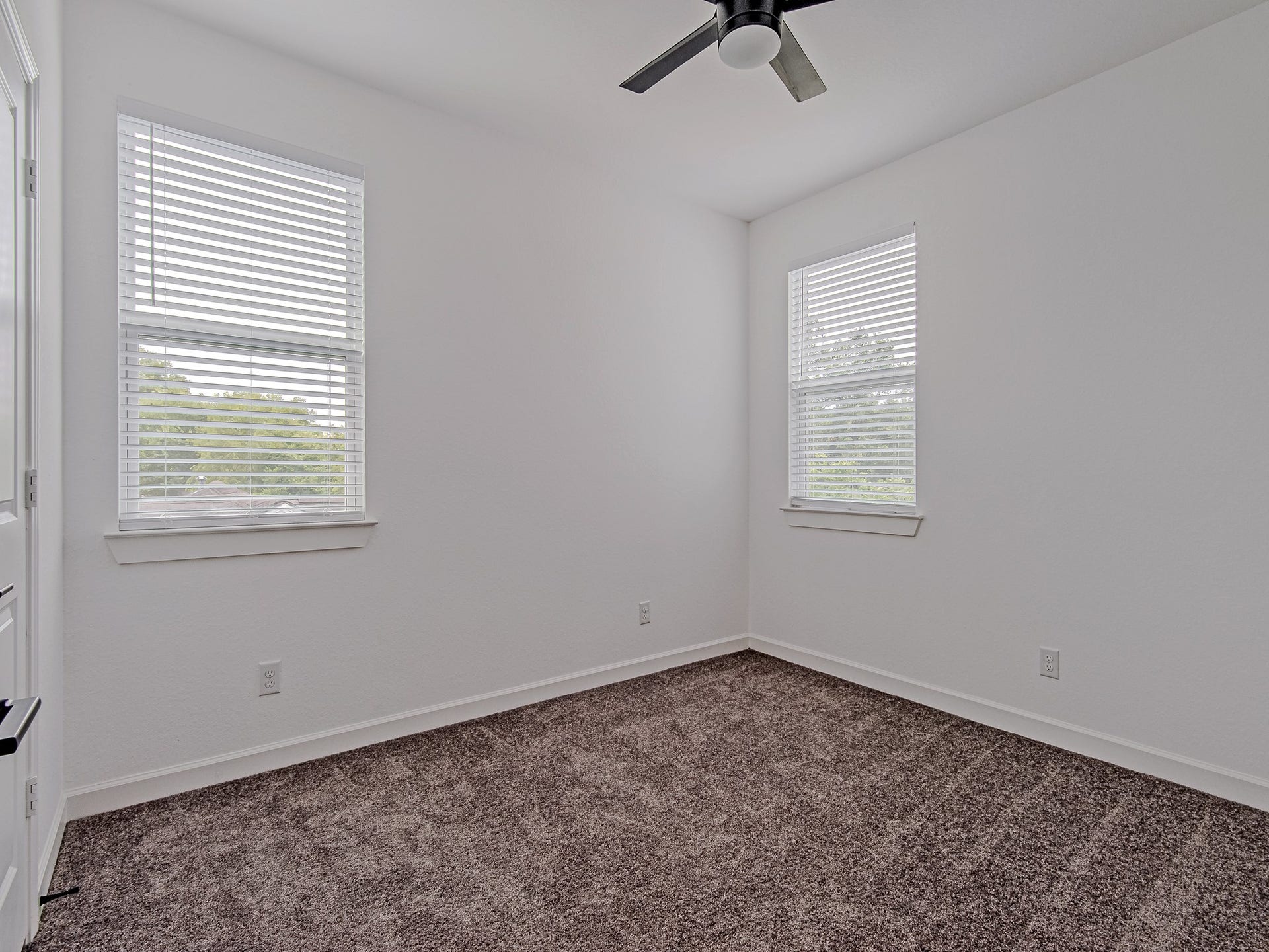 Secondary bedroom with large windows, soft carpeting, and a bright, neutral color palette.