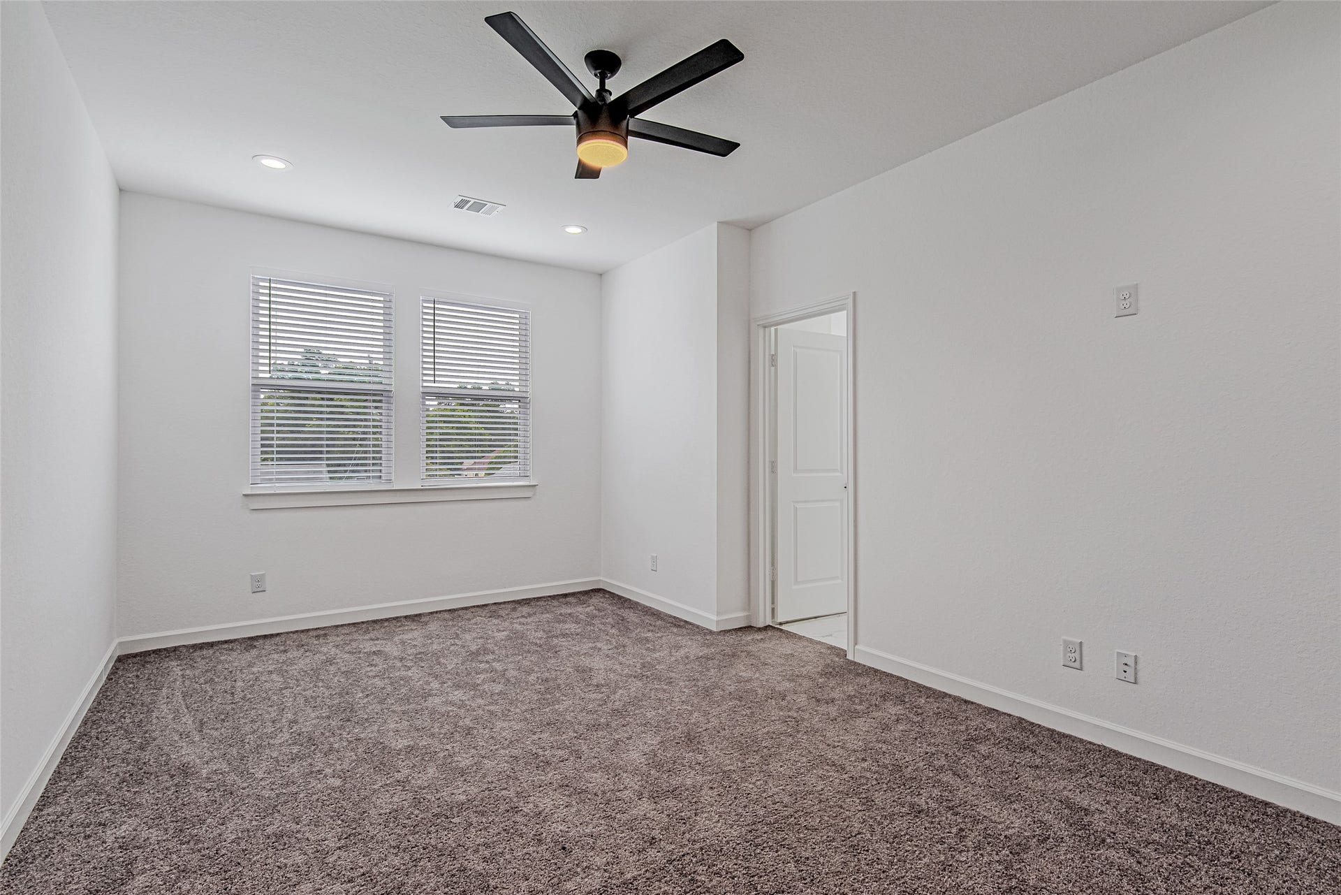 Comfortable secondary bedroom with plush carpeting, ceiling fan, and natural light.