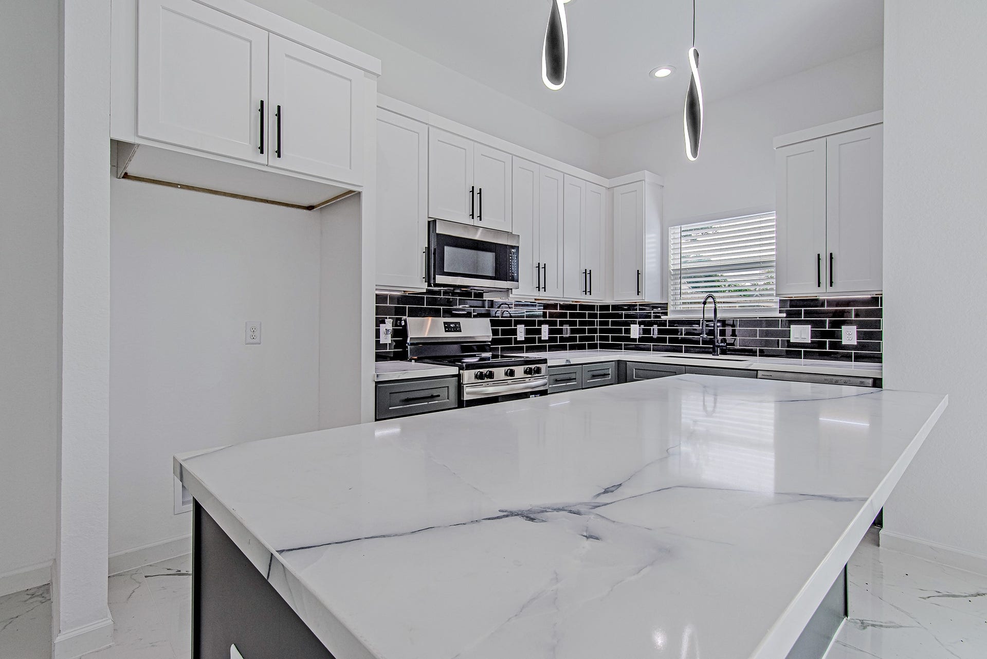 Kitchen featuring quartz countertops, modern finishes, abundant cabinetry, and a spacious island.