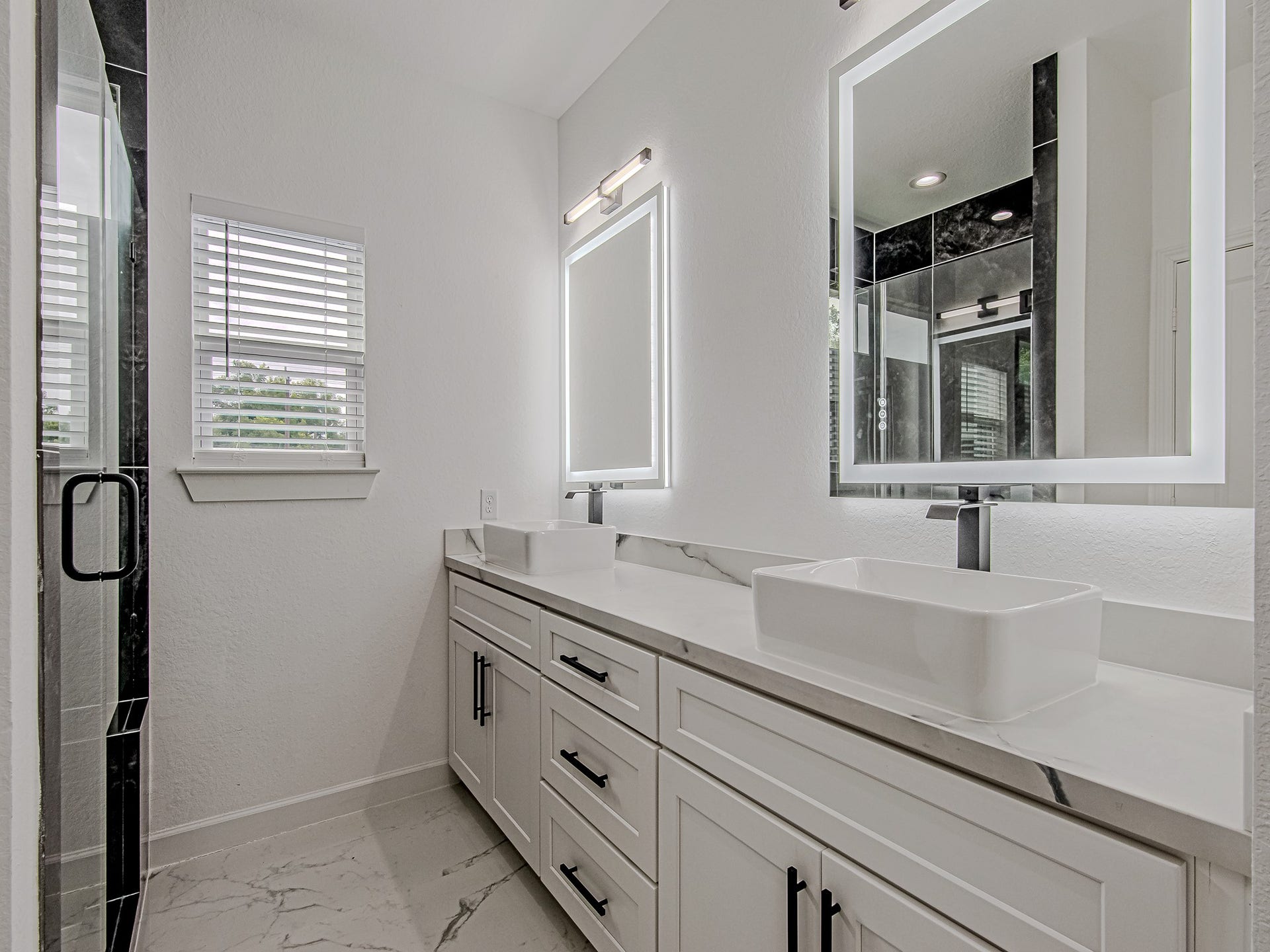 Primary bathroom featuring dual sinks, generous counter space, and a bright, modern design.