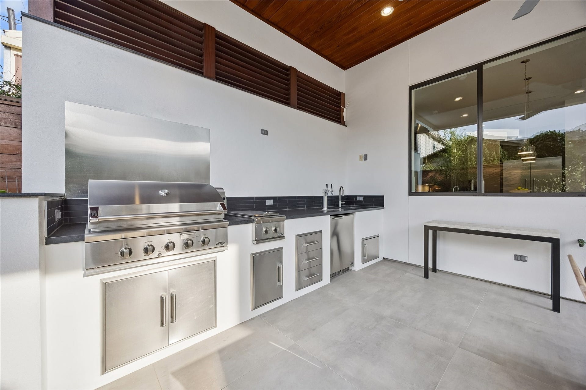 Elevate your outdoor living with a premium setup featuring a 36-inch grill, dual side burner, keg system, sink, and ample storage. Perfect for cooking and entertaining in a comfortable, sheltered space.