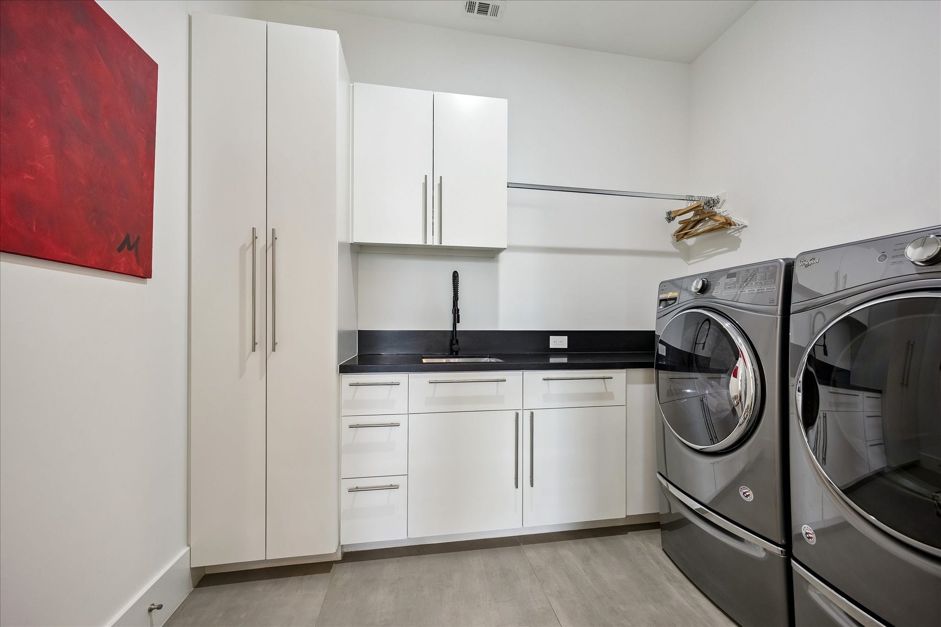 Custom built-ins and cabinets provide ample storage in this stylish laundry room, complete with a convenient separate sink for added functionality.