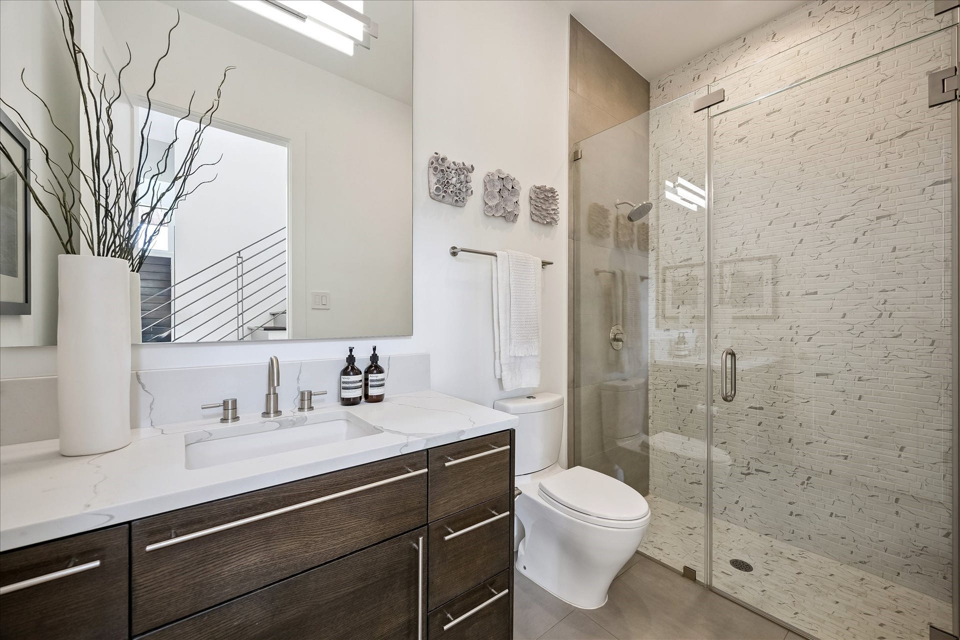Elegant downstairs full bath with sleek quartz countertops and a spacious walk-in shower, combining style and functionality.