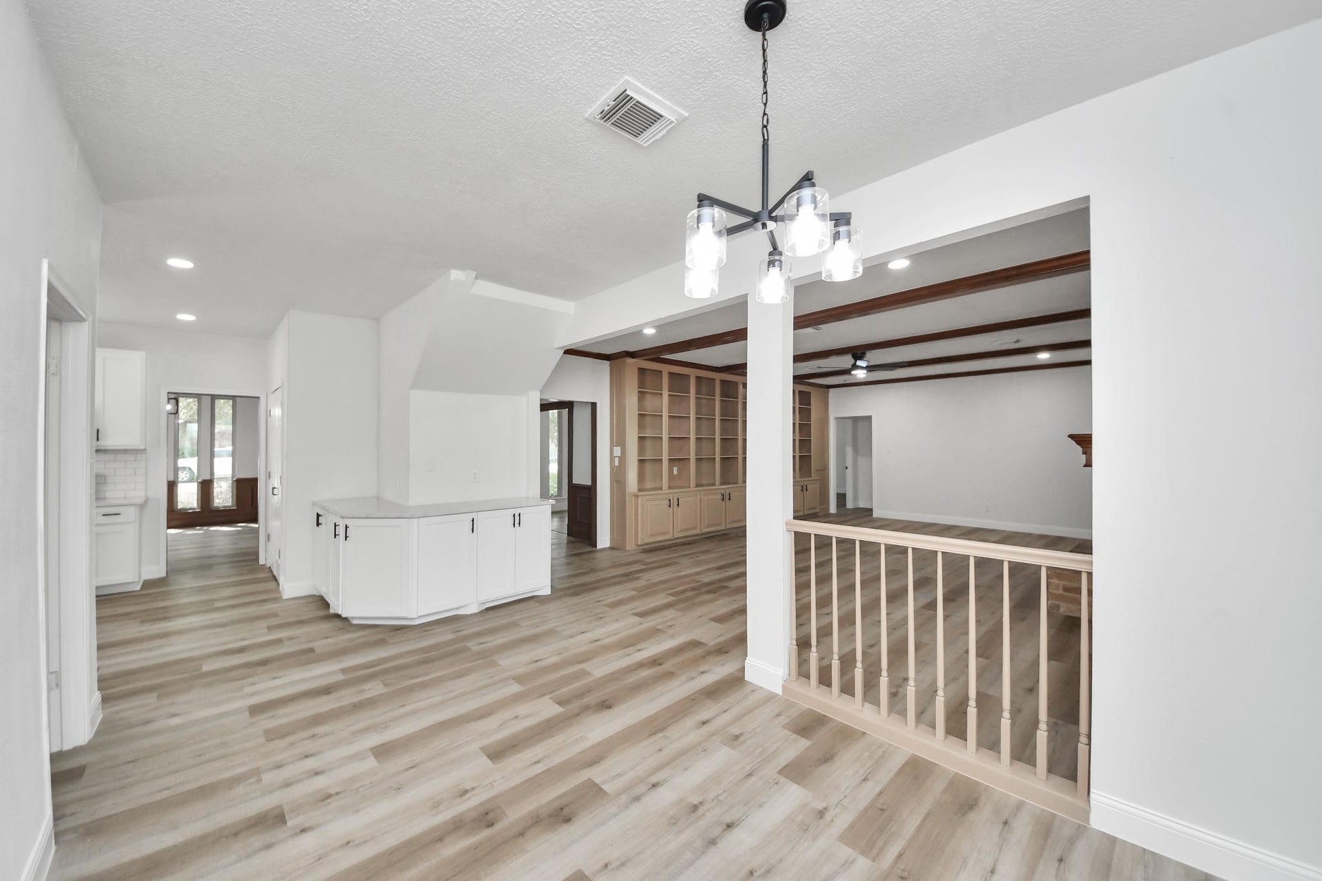 8503 Rebawood Drive, Humble, TX 77346 Spacious open-concept living area featuring elegant wood flooring, built-in shelving, and modern light fixtures, seamlessly connecting to the kitchen and dining spaces.