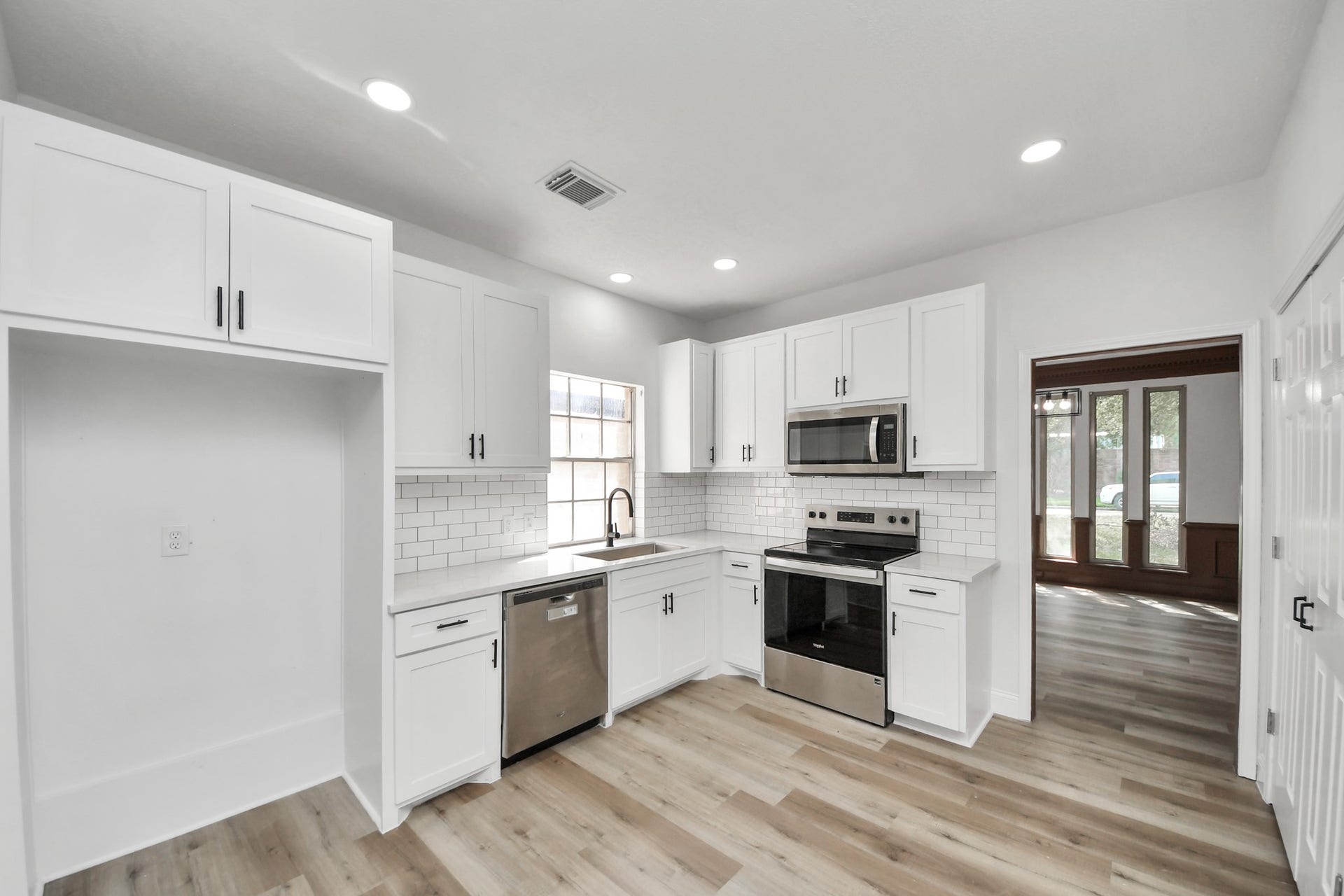 8503 Rebawood Drive, Humble, TX 77346 Modern kitchen with sleek white cabinetry, stainless steel appliances, and stylish subway tile backsplash, offering ample natural light and a spacious layout.