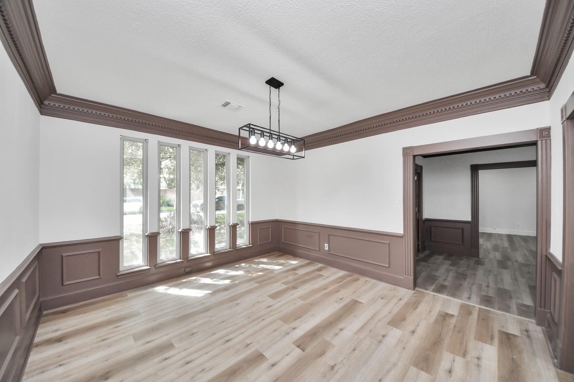 8503 Rebawood Drive, Humble, TX 77346 Bright dining area with large windows, elegant wainscoting, and modern light fixture, offering a warm and inviting space for gatherings.