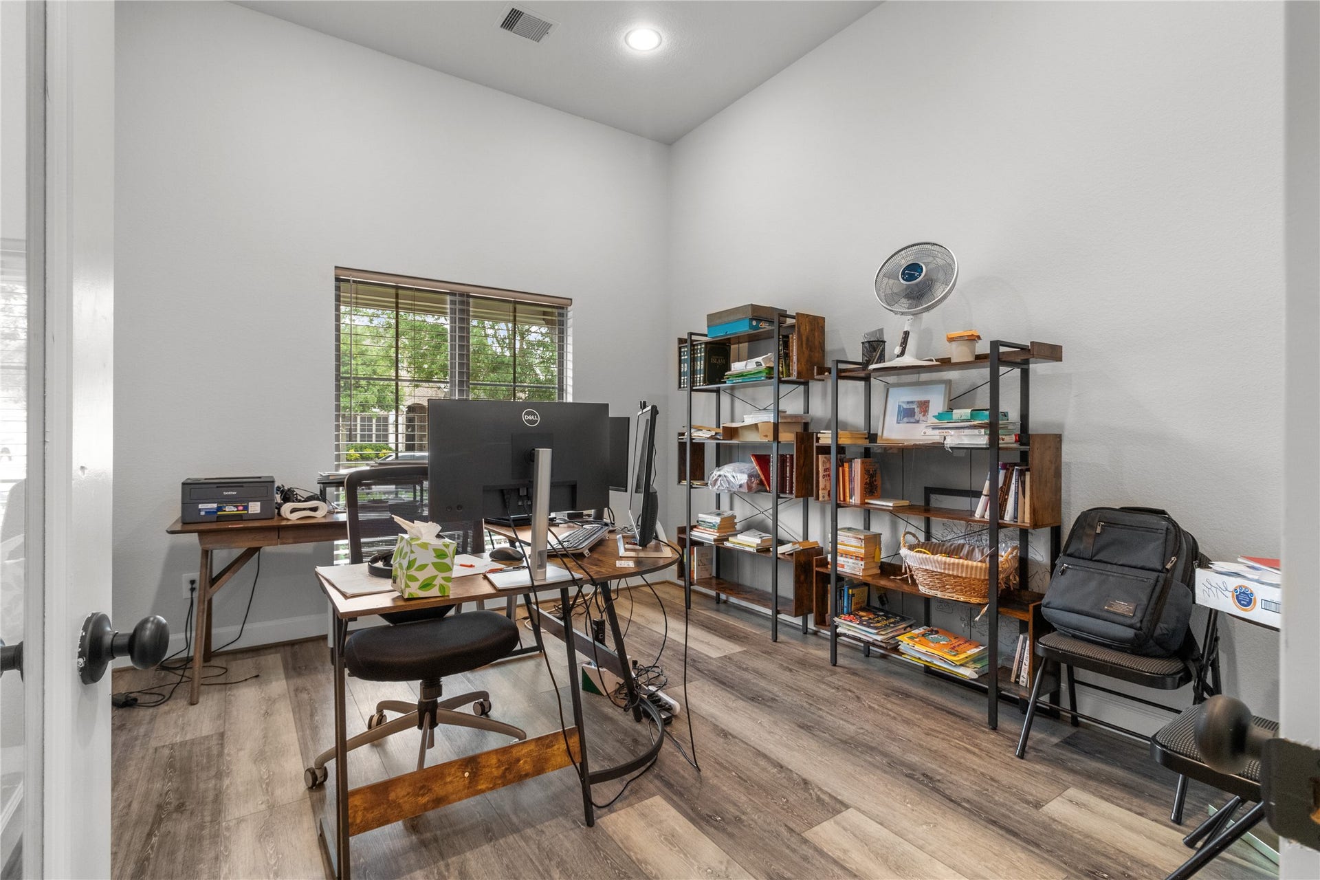 30427 Watershed Way, Fulshear, TX 77441 This is a bright home office with large windows, modern wood flooring, and ample shelving for storage. It features a spacious desk area suitable for work or study.