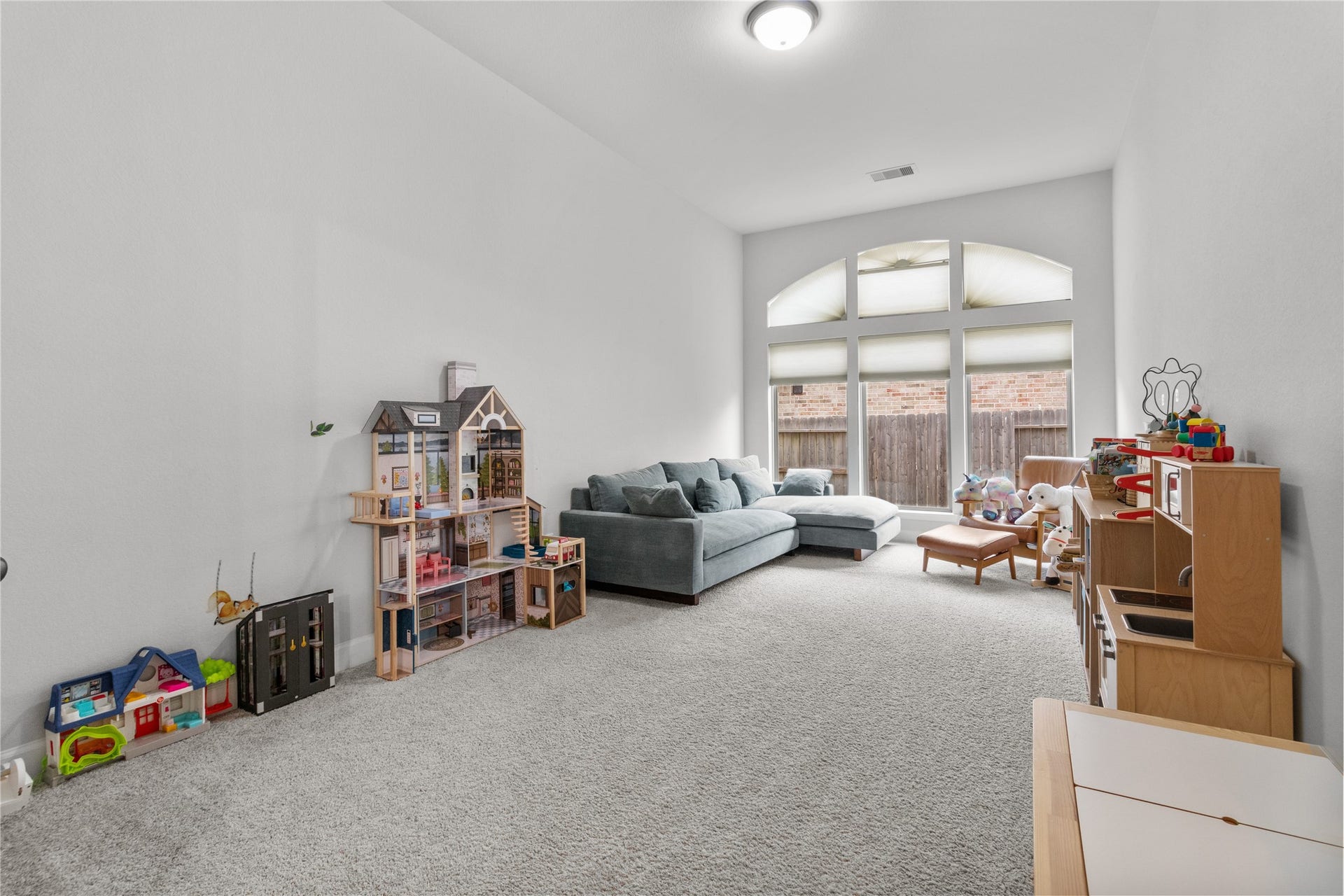 30427 Watershed Way, Fulshear, TX 77441 This spacious, carpeted room is perfect for a play area or family space. It features large windows for natural light, a cozy couch, and plenty of room for toys and activities.