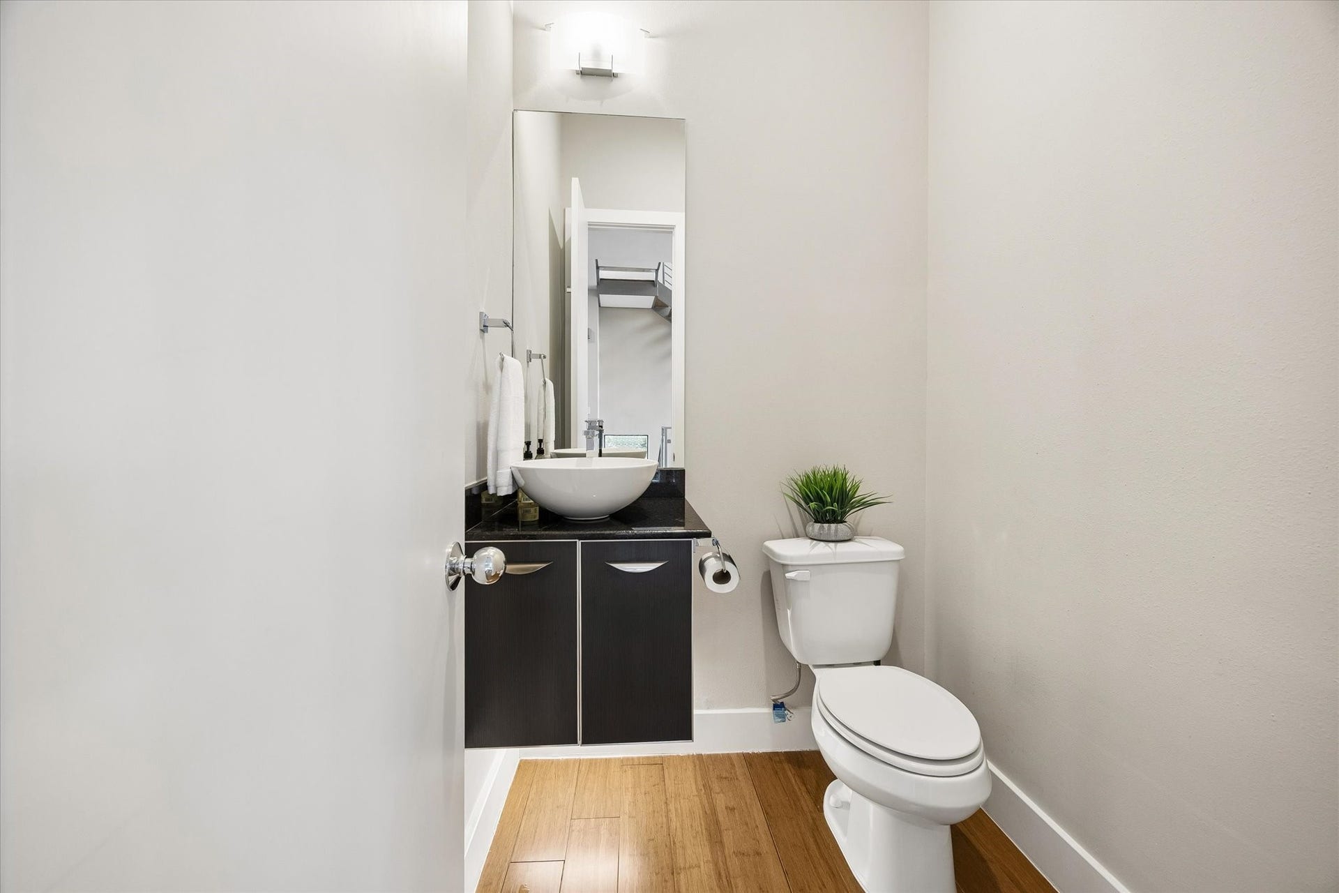The main floor powder bath is convenient for daily use and guests, with a clean modern look that fits right in with the rest of the home. A floating vanity, vessel sink, and under-cabinet lighting add a stylish touch to this practical everyday space.