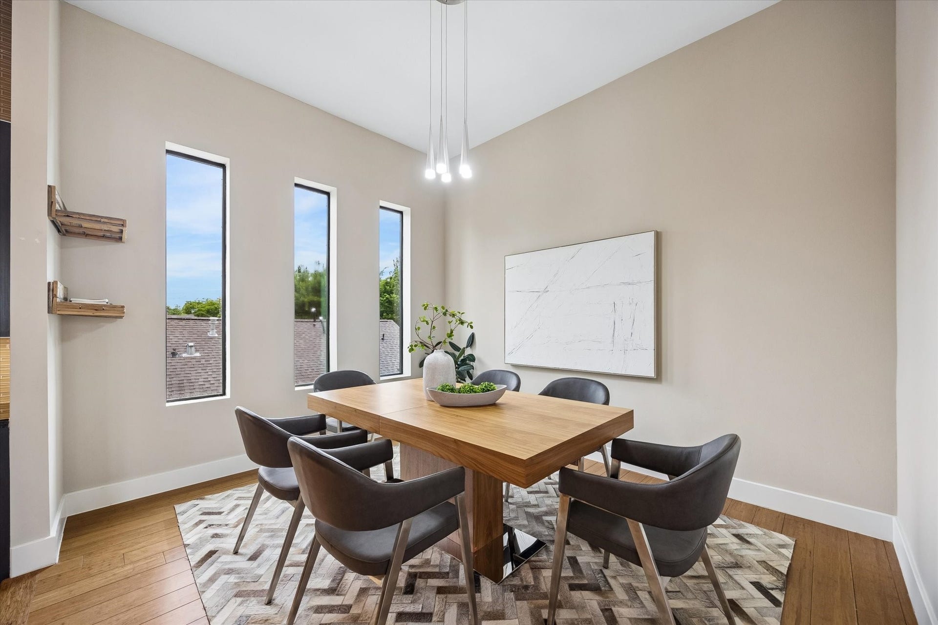 This dining area feels bright, comfortable, and easy to enjoy, with tall windows, warm wood flooring, and sleek overhead lighting that adds a modern touch. It is the kind of space that works just as well for casual weeknight dinners as it does for hosting friends.