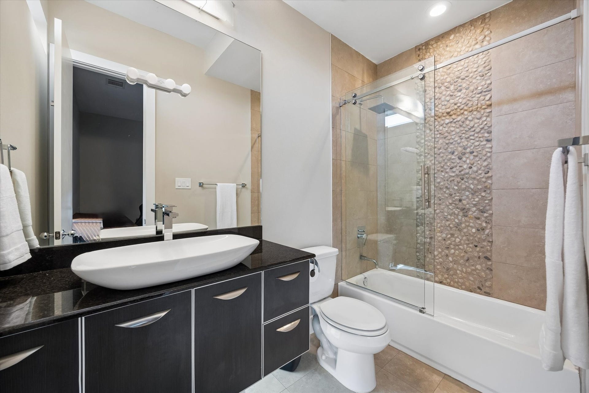 Guests will love having their own private ensuite bath, complete with a sleek vessel sink, plenty of storage, and a beautifully tiled tub and shower combo. It's a stylish, comfortable setup that makes the third-floor suite feel even more private and inviting.