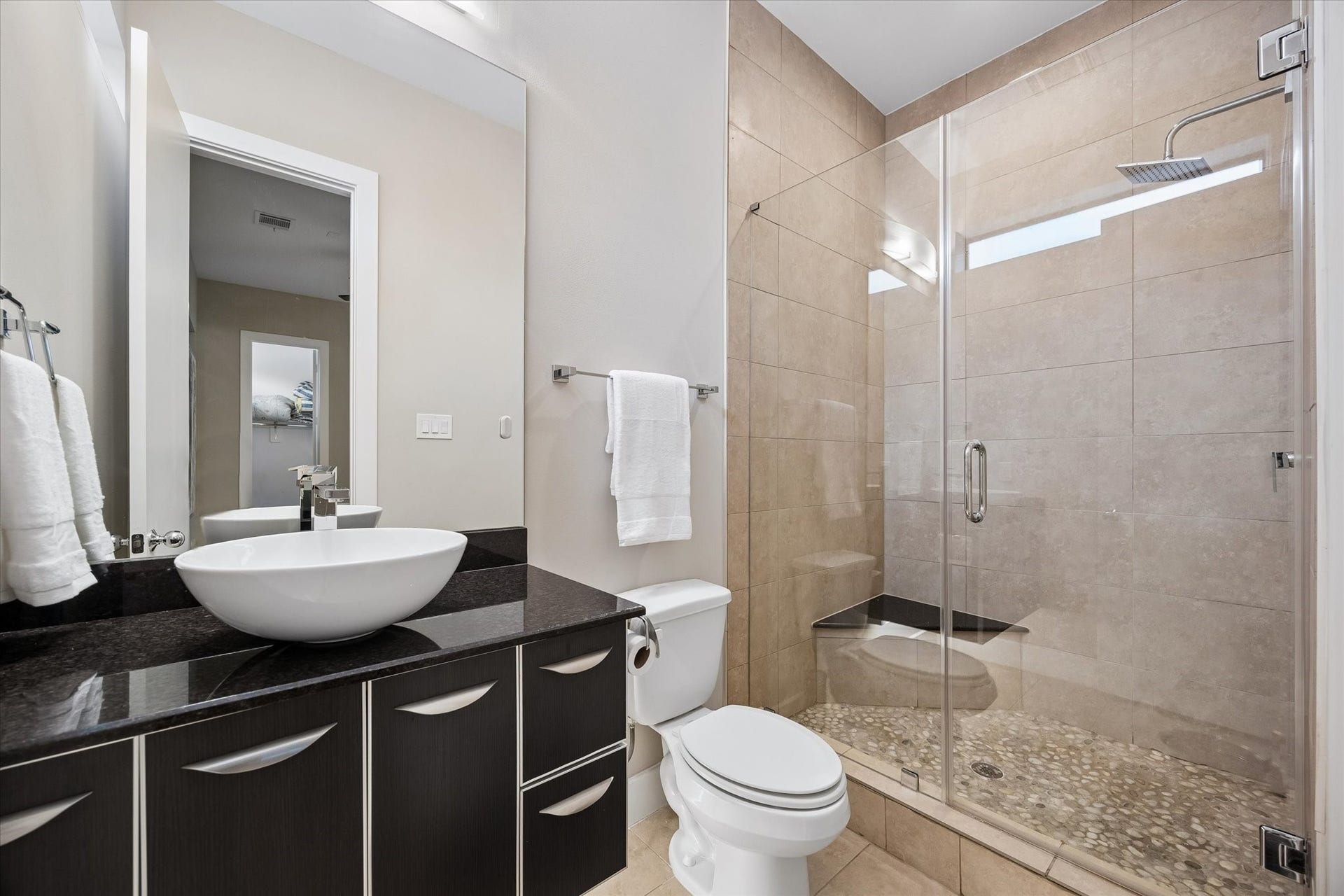 The ensuite bath adds comfort and privacy to the first-floor suite with a sleek vanity, vessel sink, and a spacious glass-enclosed shower. This thoughtful setup makes the ground floor feel like its own private retreat while keeping the floor plan flexible for real life.