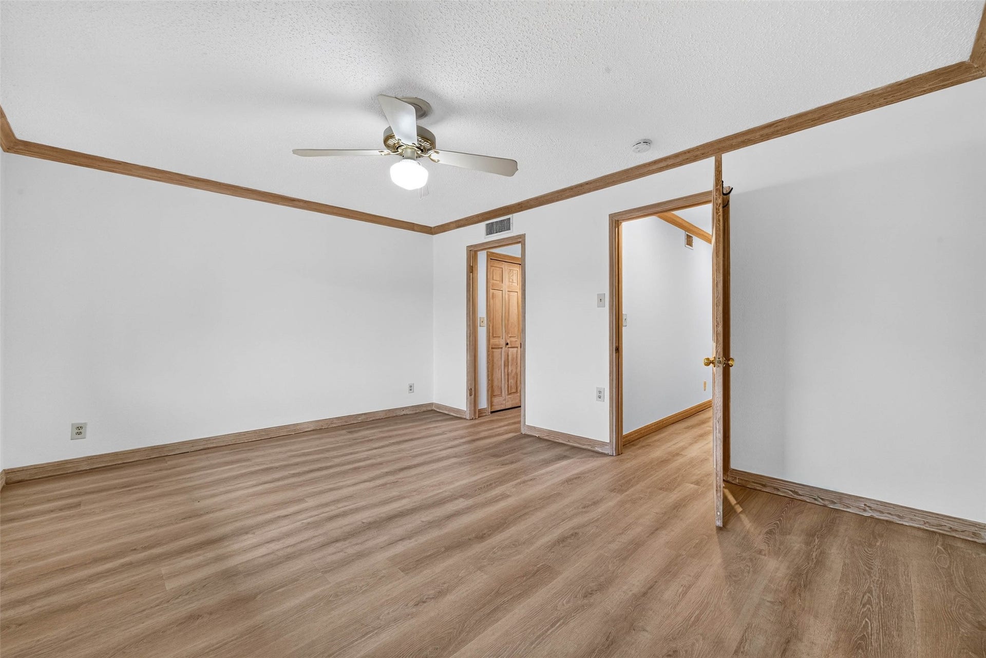 Spacious room featuring elegant flooring, bright white walls, and a ceiling fan for comfort.