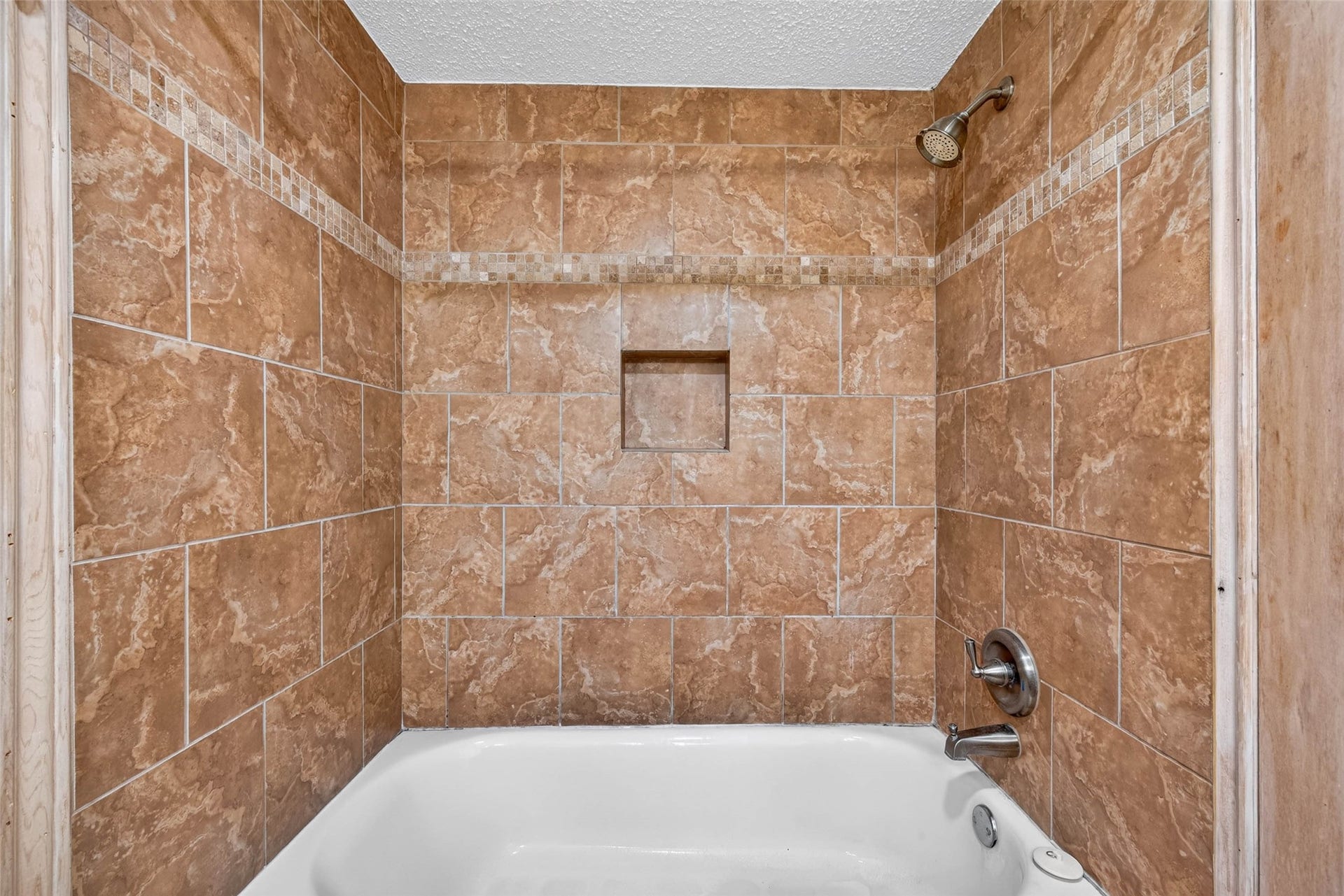 Elegant bathroom featuring a bathtub with stylish brown tile surround