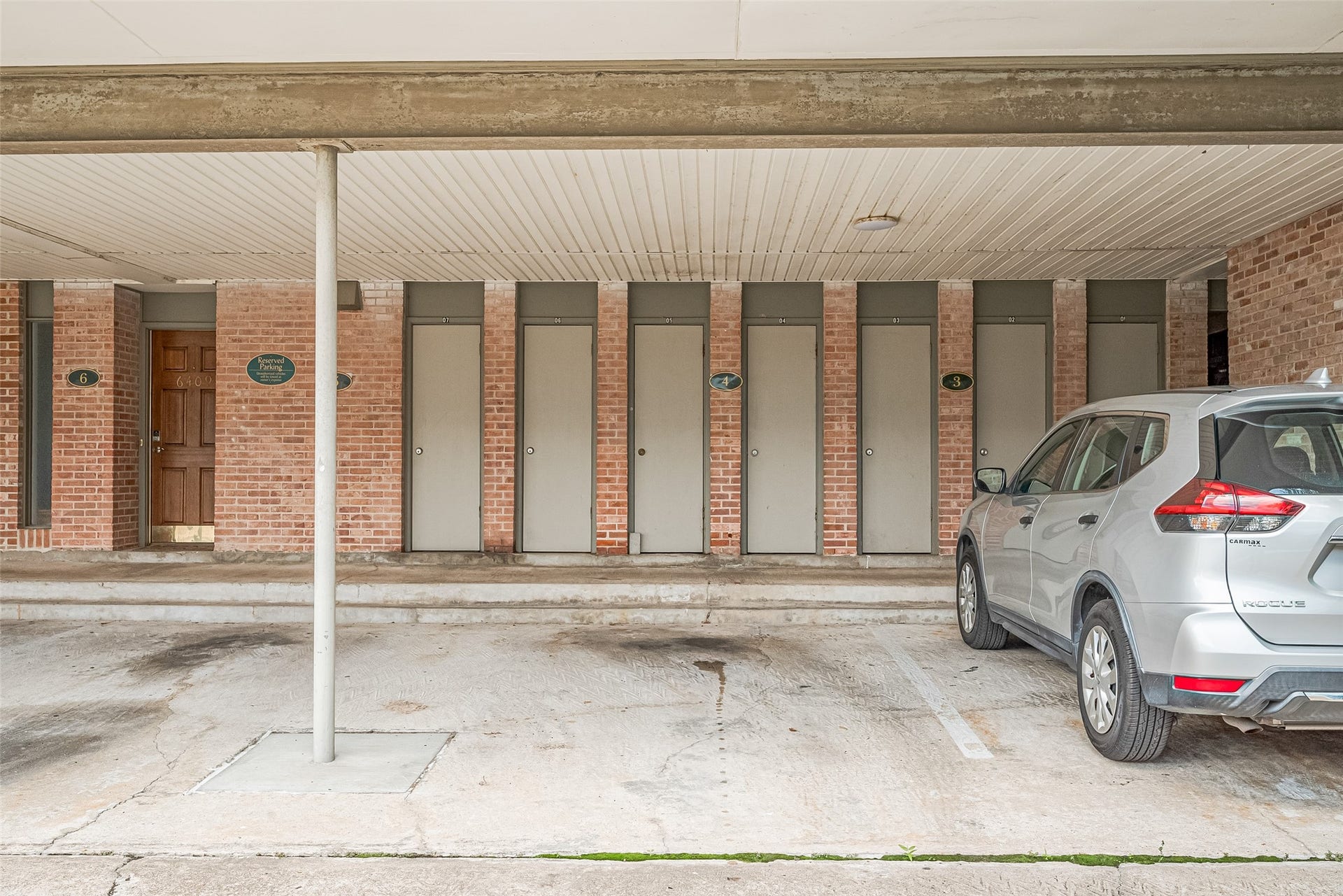Covered parking area with secure storage units and brick exterior, providing convenience and functionality.