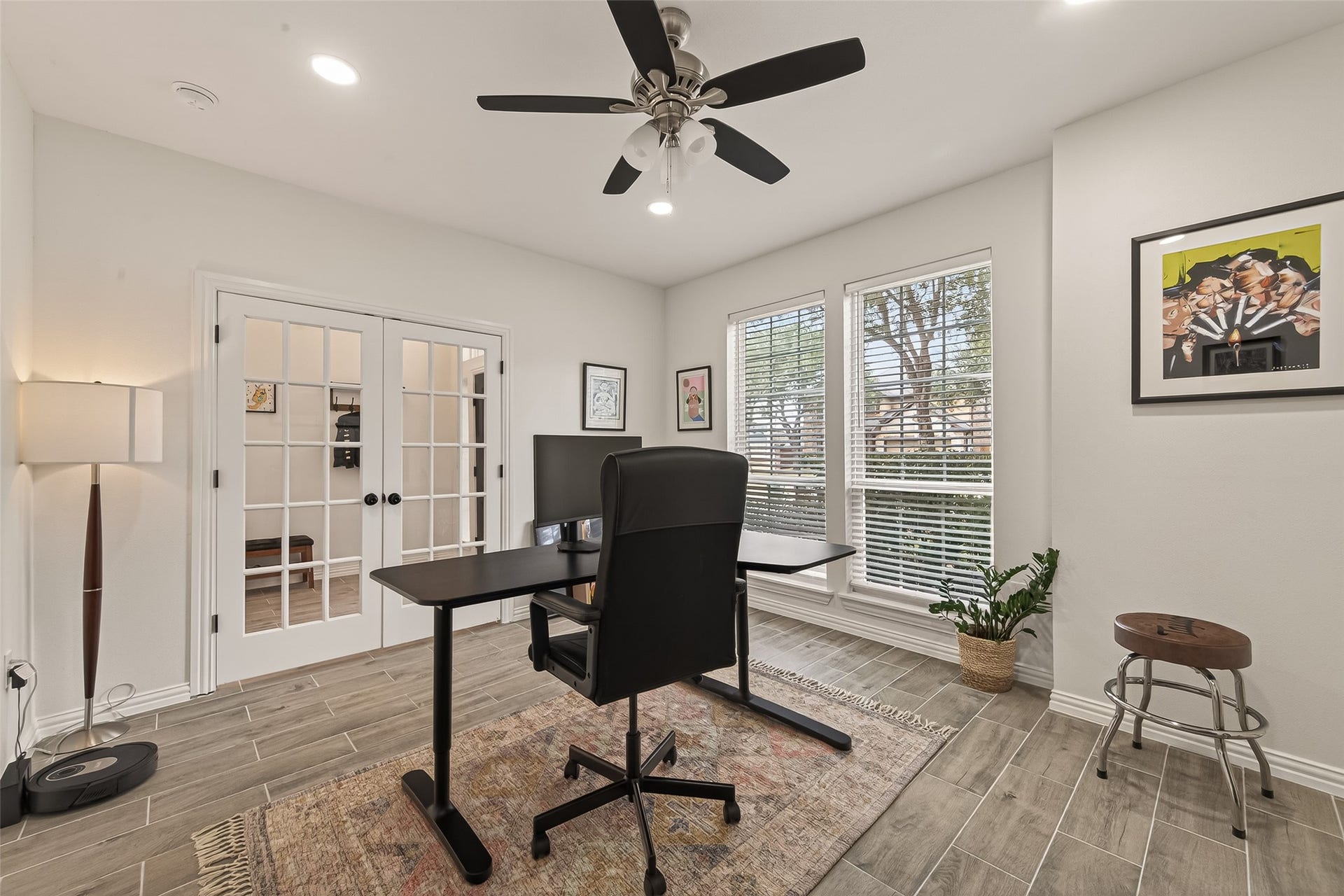 4423 Parkwater Cove Court SE, Sugar Land, TX 77479 This photo showcases a bright, modern home office with large windows, a ceiling fan, and French doors, creating a functional yet inviting workspace.