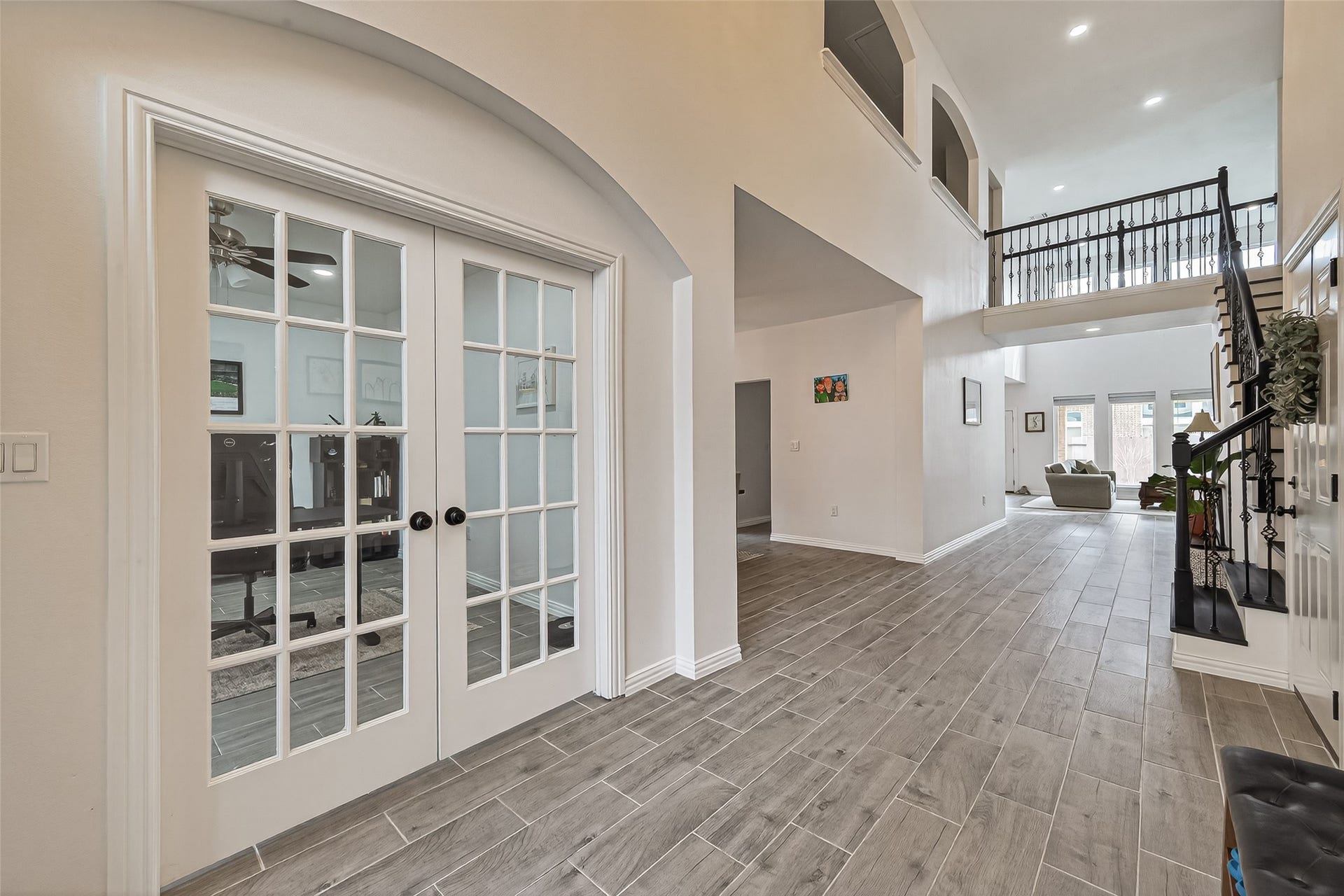 4423 Parkwater Cove Court SE, Sugar Land, TX 77479 This spacious entryway features high ceilings and elegant tile flooring. French doors open to a bright office or study, and a wrought-iron staircase leads to an upper level. The open layout extends to a living area with large windows for natural light.