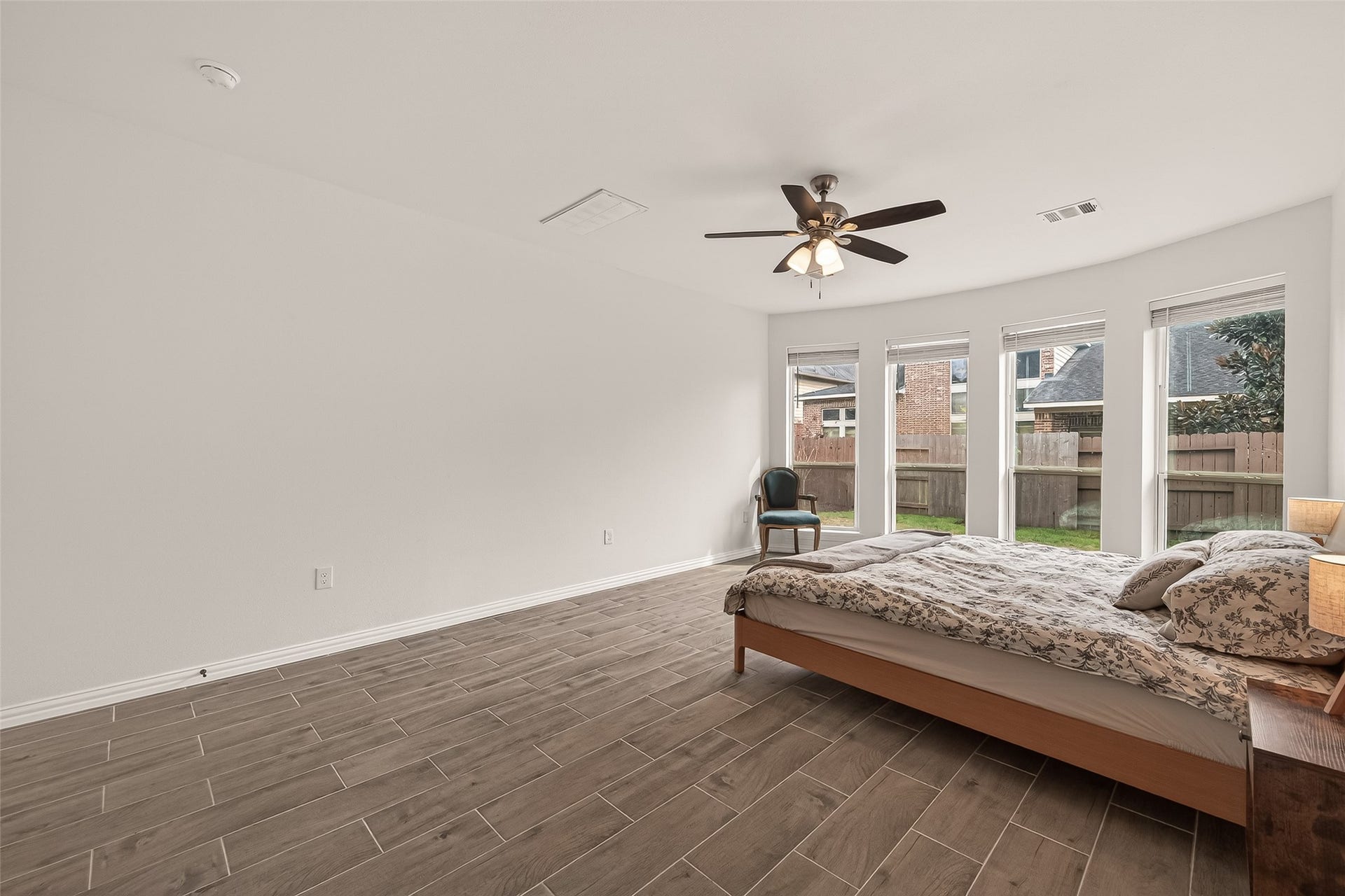 4423 Parkwater Cove Court SE, Sugar Land, TX 77479 This spacious bedroom features sleek tile flooring, a ceiling fan, and ample natural light from large windows overlooking the backyard. The neutral walls offer a modern look, perfect for personalization.