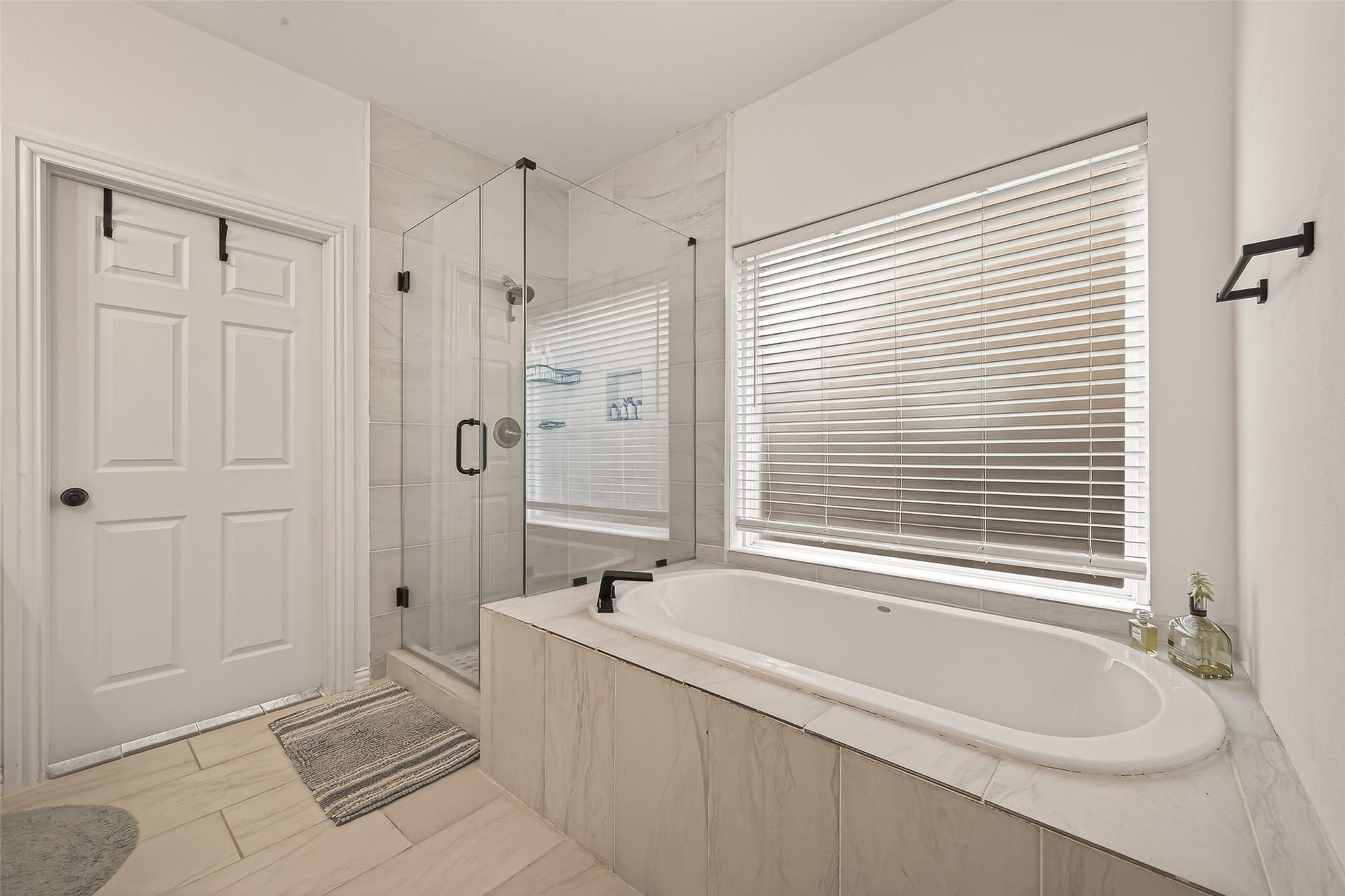 4423 Parkwater Cove Court SE, Sugar Land, TX 77479 This bathroom features a modern, spa-like design with a spacious glass-enclosed shower, a large soaking tub, and sleek fixtures. Natural light streams through the window with blinds, creating a serene atmosphere.