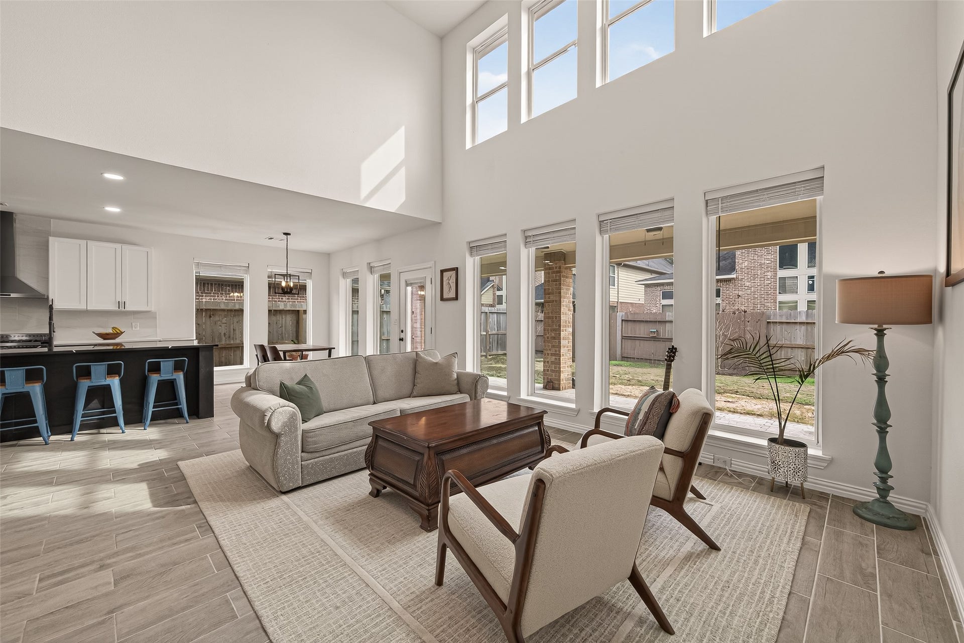 4423 Parkwater Cove Court SE, Sugar Land, TX 77479 This photo showcases a spacious, open-concept living area with high ceilings and abundant natural light. It features a modern kitchen with a breakfast bar, a cozy seating area, and large windows overlooking the backyard. The neutral tones and elegant finishes create a welcoming, airy atmosphere.