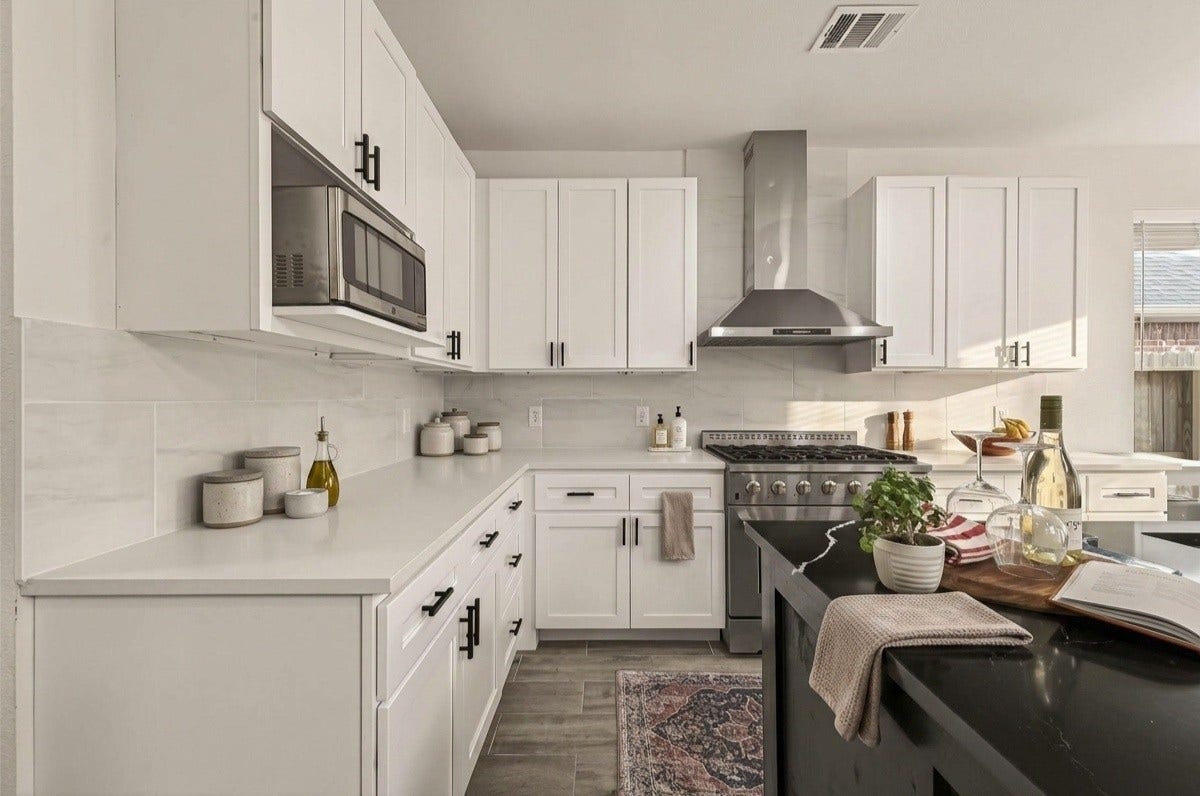 4423 Parkwater Cove Court SE, Sugar Land, TX 77479 This modern kitchen features sleek white cabinetry and stainless steel range hood, The black countertops add a stylish contrast, while a large window brings in natural light. Perfect for both cooking and entertaining.