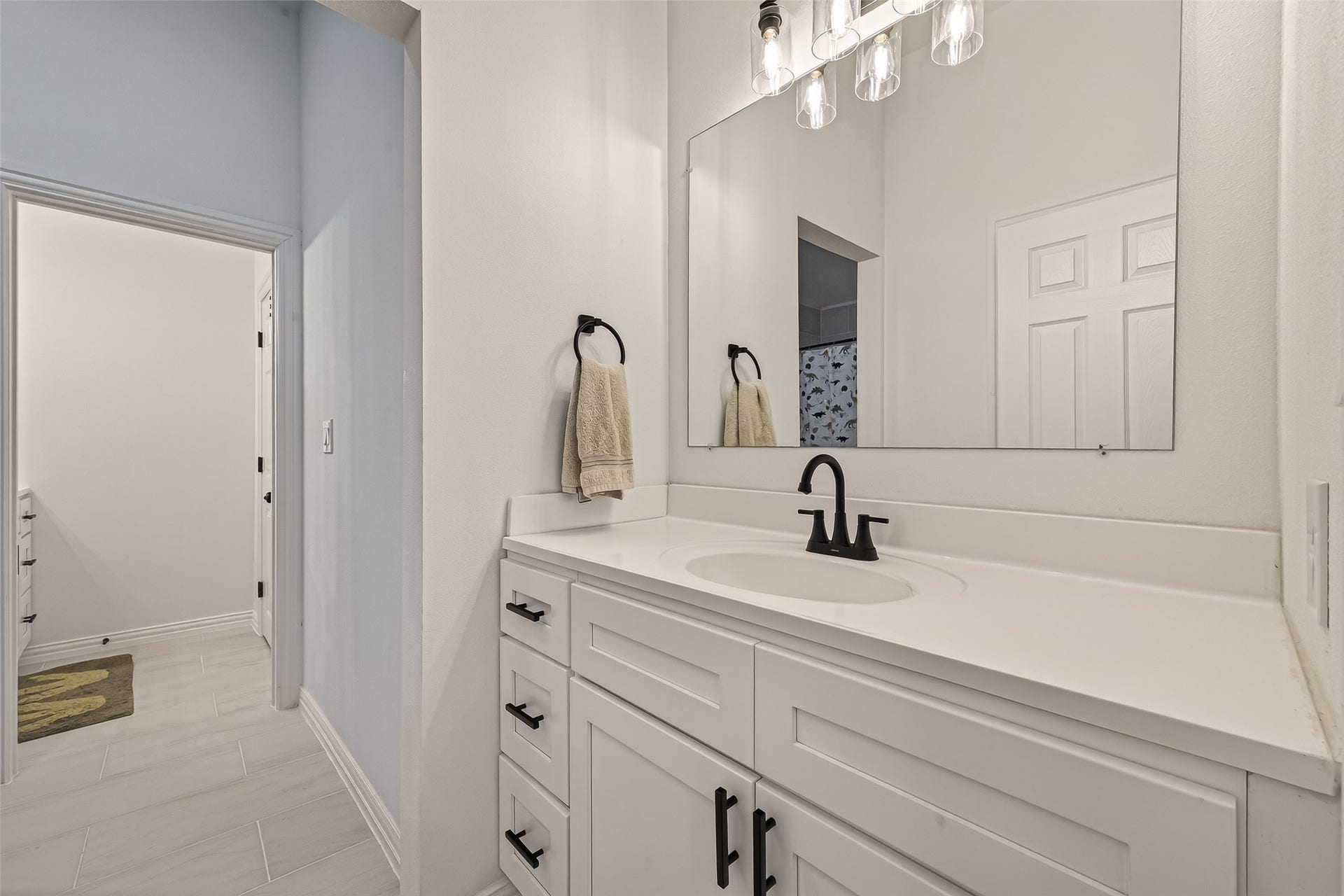 4423 Parkwater Cove Court SE, Sugar Land, TX 77479 This photo showcases a modern bathroom with a sleek white vanity, black fixtures, and a large mirror. The space is bright with ample lighting, and there's a glimpse of a hallway leading to additional rooms.